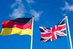 Das Bild zeigt die Deutsche und britische Flagge vor blauem Himmel
