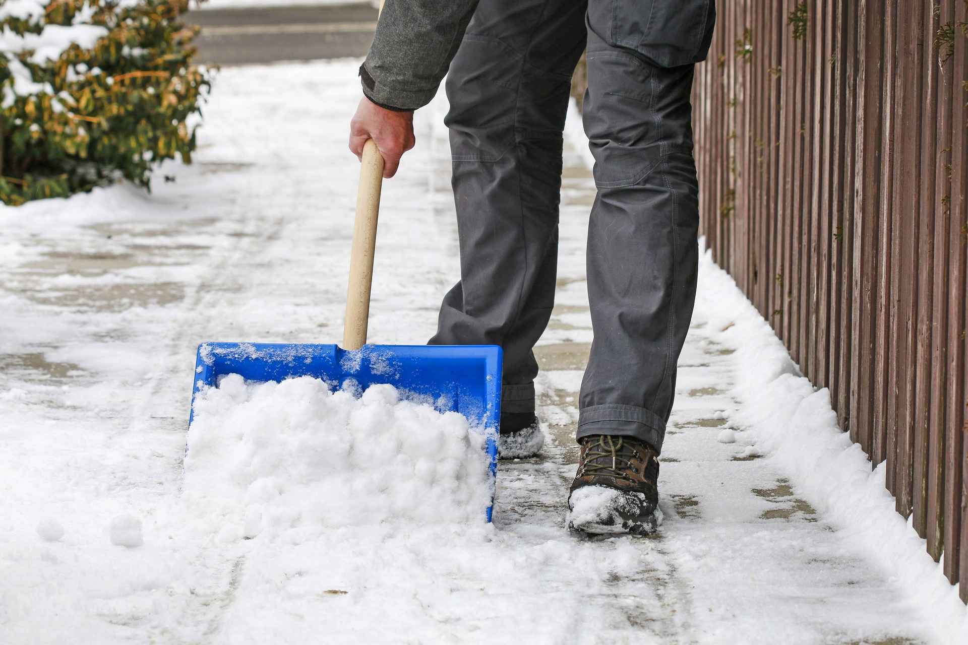 Mann schippt Schnee auf einem Bürgersteig