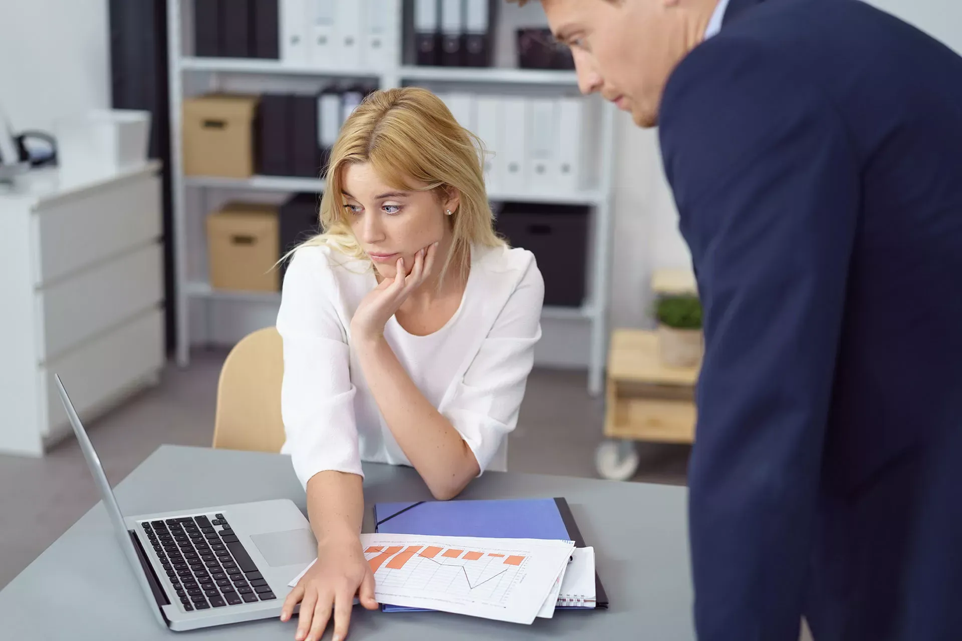 Kollegen schauen besorgt auf eine Finanzgrafik und einen Laptopbildschirm im Büro. Kollegen schauen besorgt auf eine Finanzgrafik und einen Laptopbildschirm im Büro.
