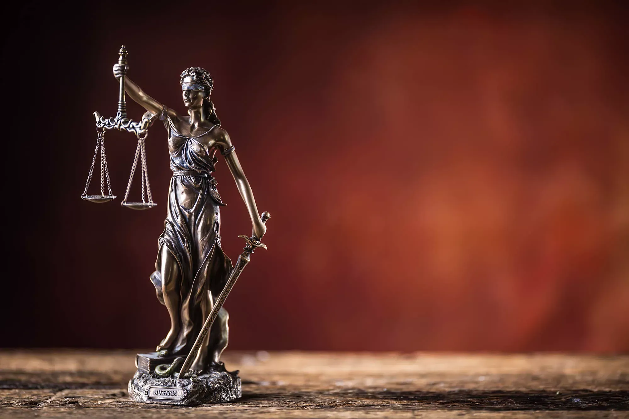 Bronzestatuette Justizia vor brauner Wand. Bronzestatuette Justizia vor brauner Wand.