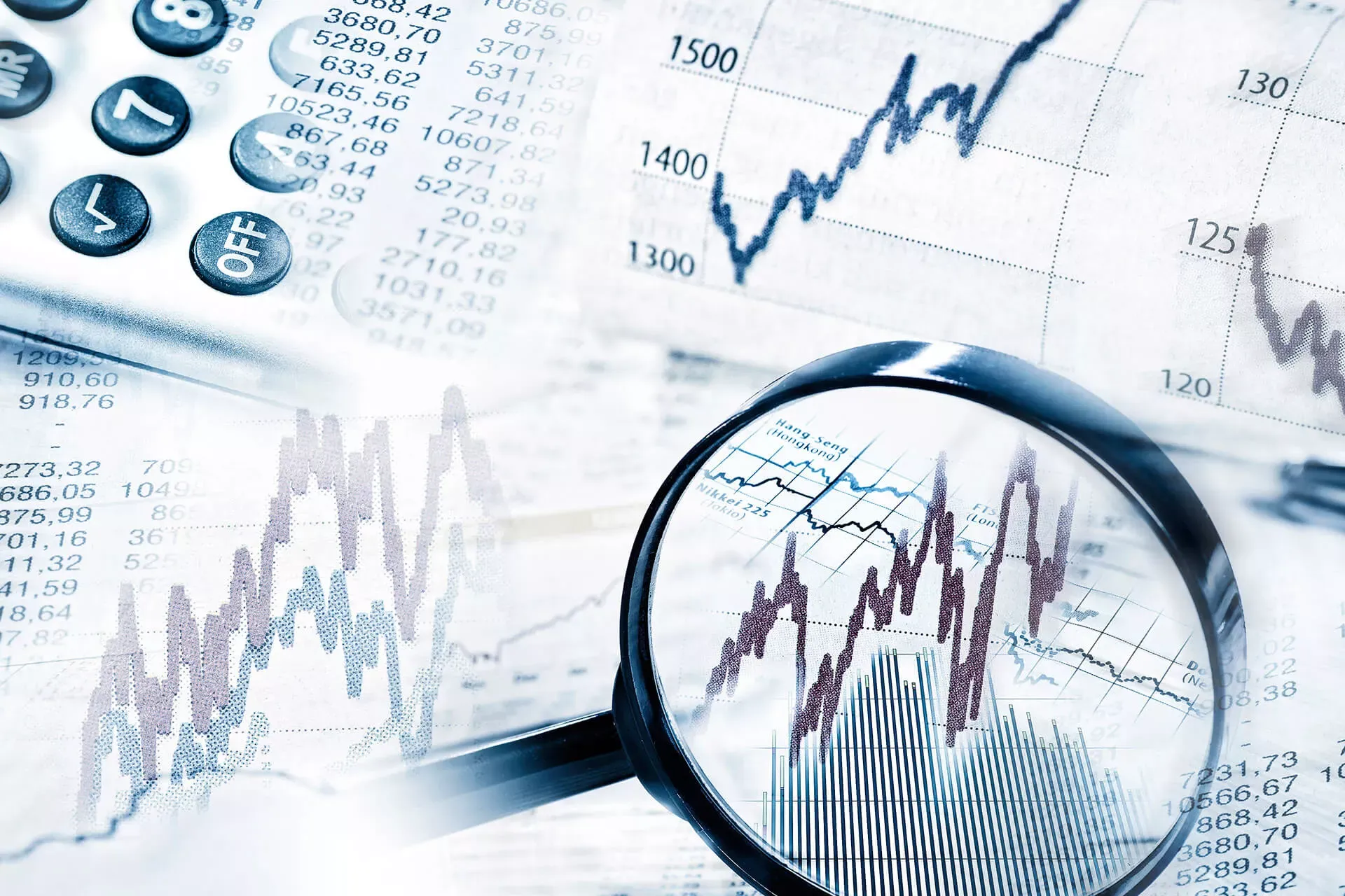 Lupe auf Aktienkursen und Finanzcharts, daneben ein Taschenrechner. Lupe auf Aktienkursen und Finanzcharts, daneben ein Taschenrechner.