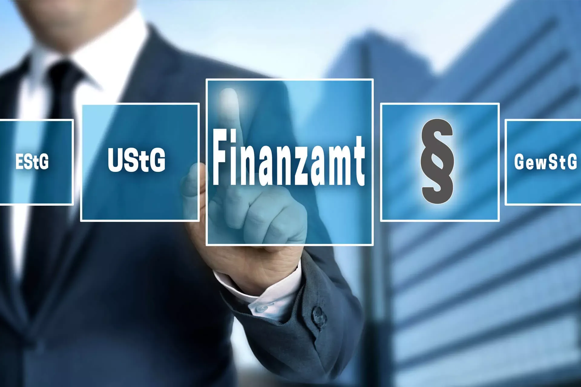 Mann in Business-Kleidung zeigt auf transparente Flächen mit der Aufschrift Finanzamt, UStG, Paragraf. GewStG. Mann in Business-Kleidung zeigt auf transparente Flächen mit der Aufschrift Finanzamt, UStG, Paragraf. GewStG.