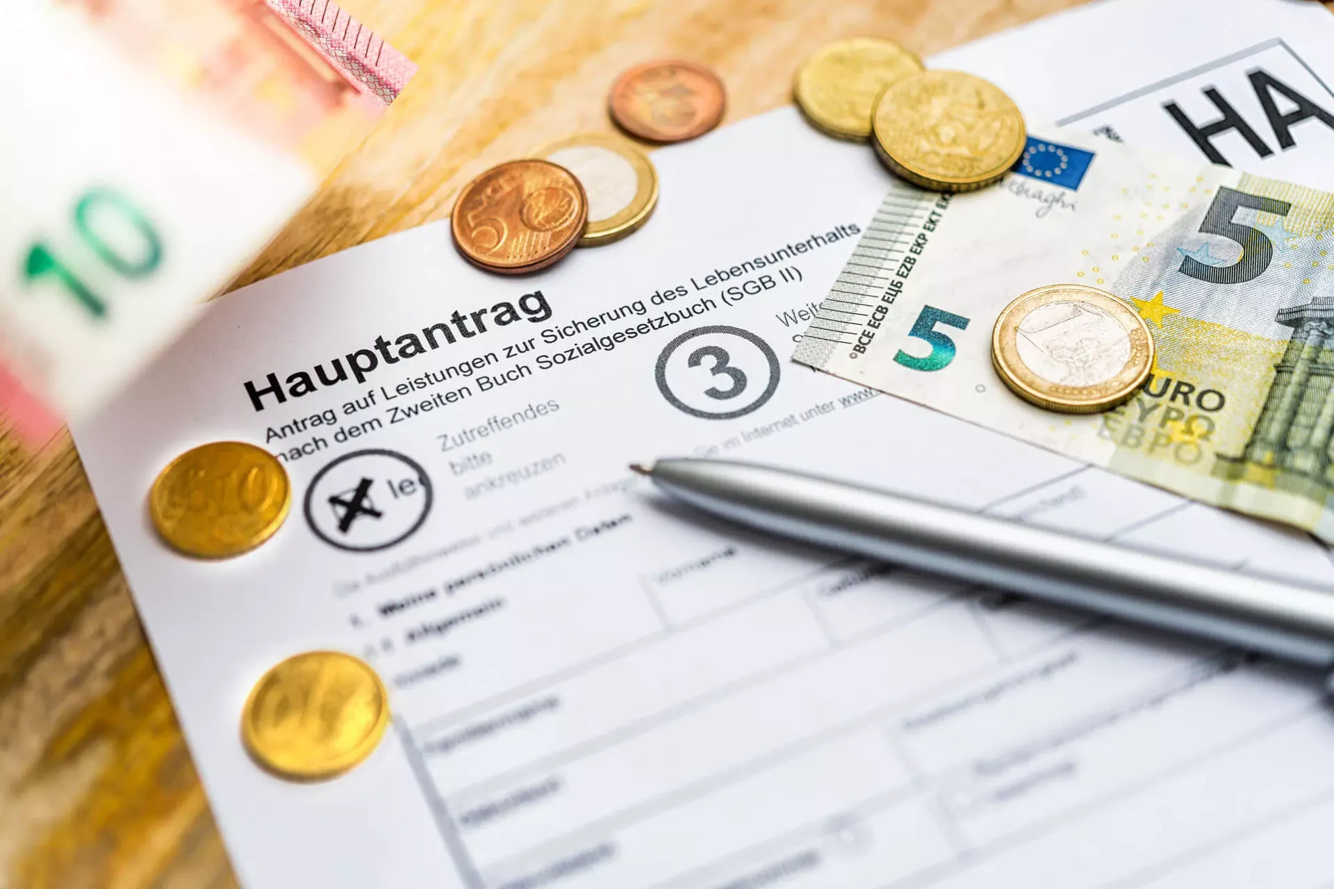 Hartz 4 Hauptantrag mit Stift, Geldmünzen und Geldscheinen. Hartz 4 Hauptantrag mit Stift, Geldmünzen und Geldscheinen.