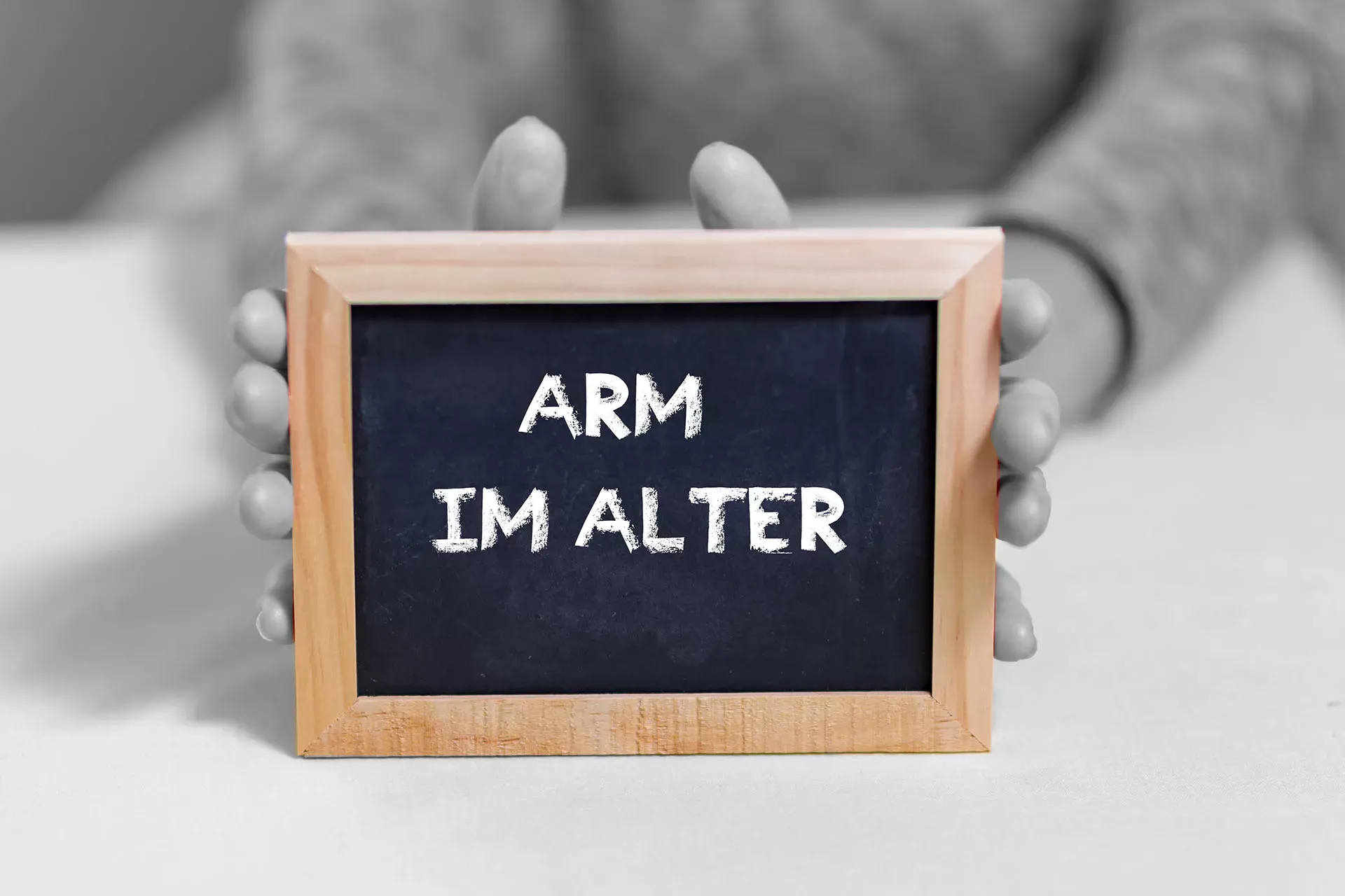 Hände halten eine kleine Schiefertafel mit Text: Arm im Alter. Hände halten eine kleine Schiefertafel mit Text: Arm im Alter.