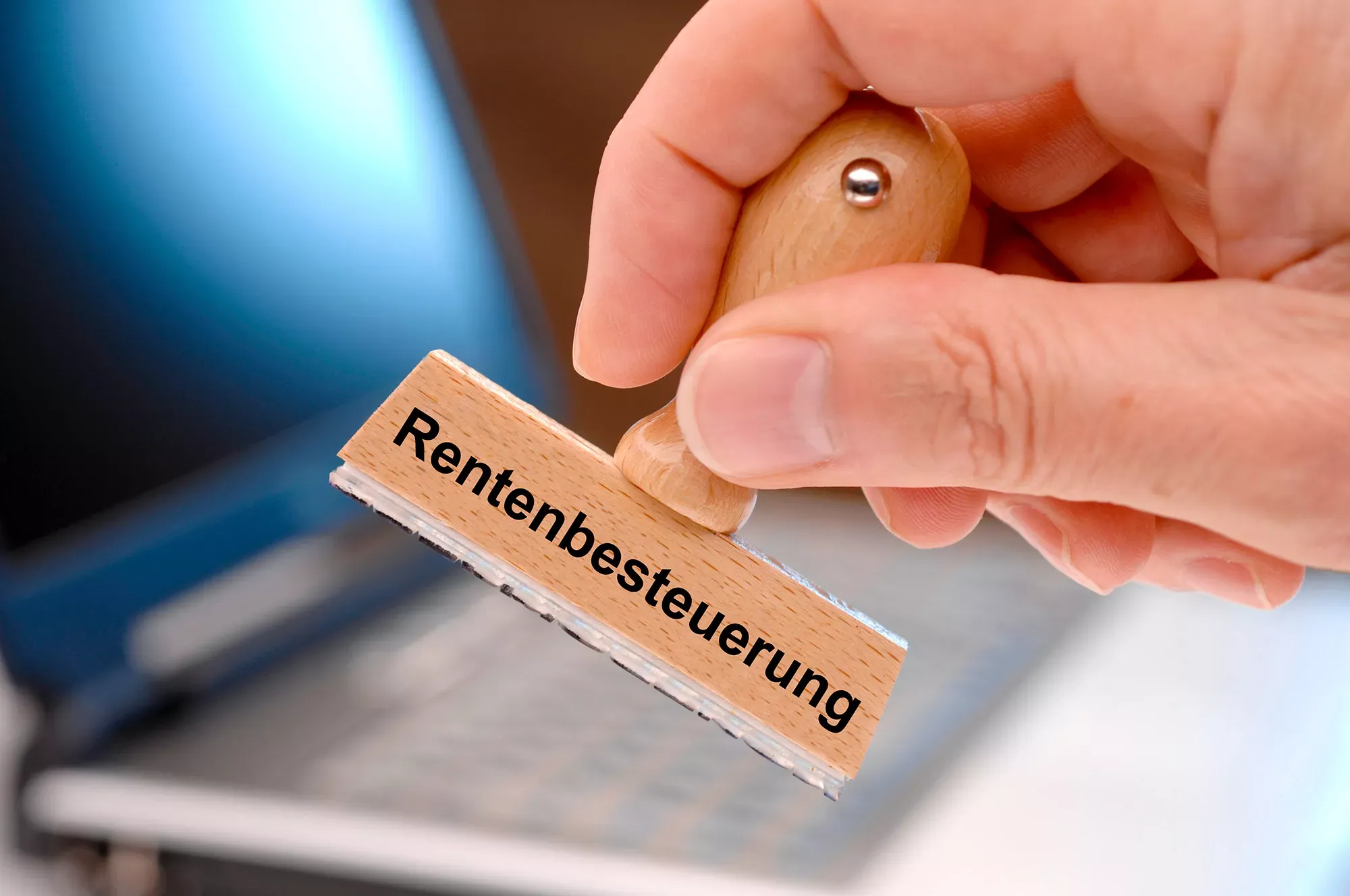 Hand hält Holzstempel mit Aufschrift Rentenbesteuerung. Hand hält Holzstempel mit Aufschrift Rentenbesteuerung.