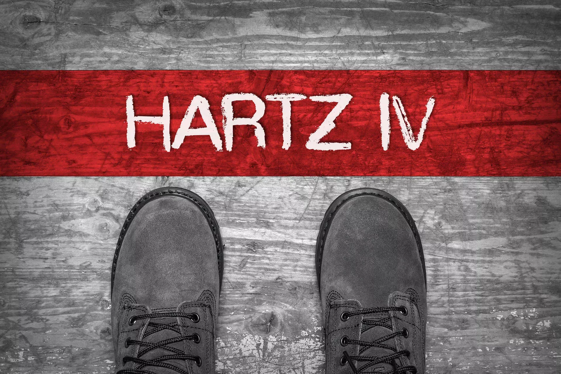 Ein Paar Schuhe stehen vor einem roten Streifen, auf dem in weiß Hartz IV steht. Ein Paar Schuhe stehen vor einem roten Streifen, auf dem in weiß Hartz IV steht.