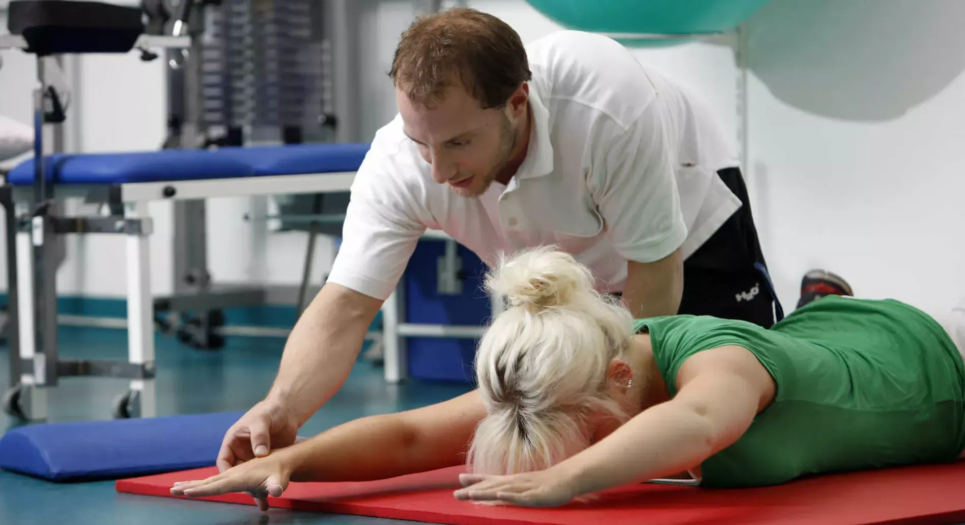 Physiotherapeut hilft Frau bei Übung am Boden. Bild: IMAGO / Jochen Tack Physiotherapeut hilft Frau bei Übung am Boden. Bild: IMAGO / Jochen Tack