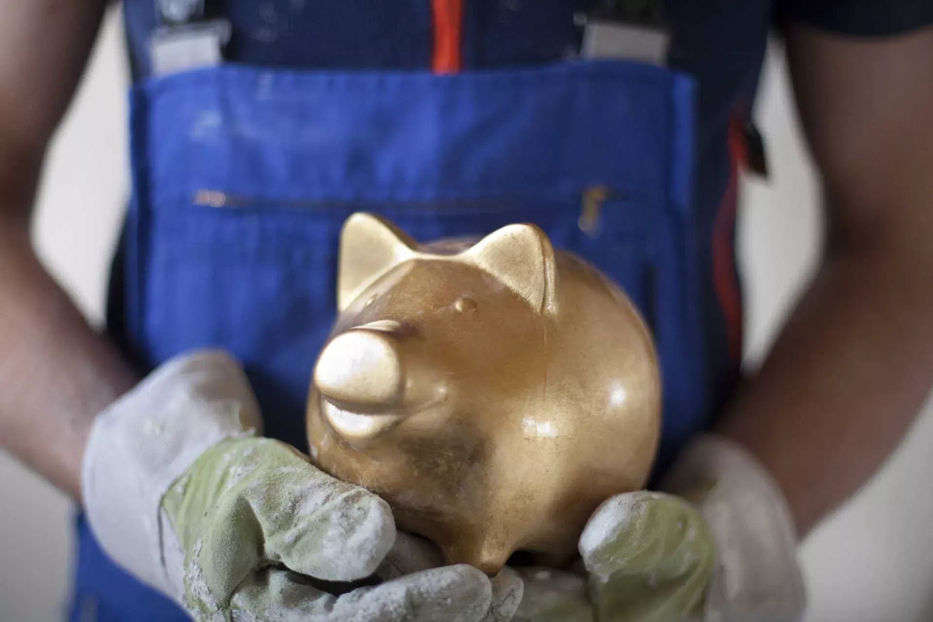 Baurarbeiter hält goldenes Sparschwein. Bild: IMAGO / photothek / Ute Grabowsky Baurarbeiter hält goldenes Sparschwein. Bild: IMAGO / photothek / Ute Grabowsky