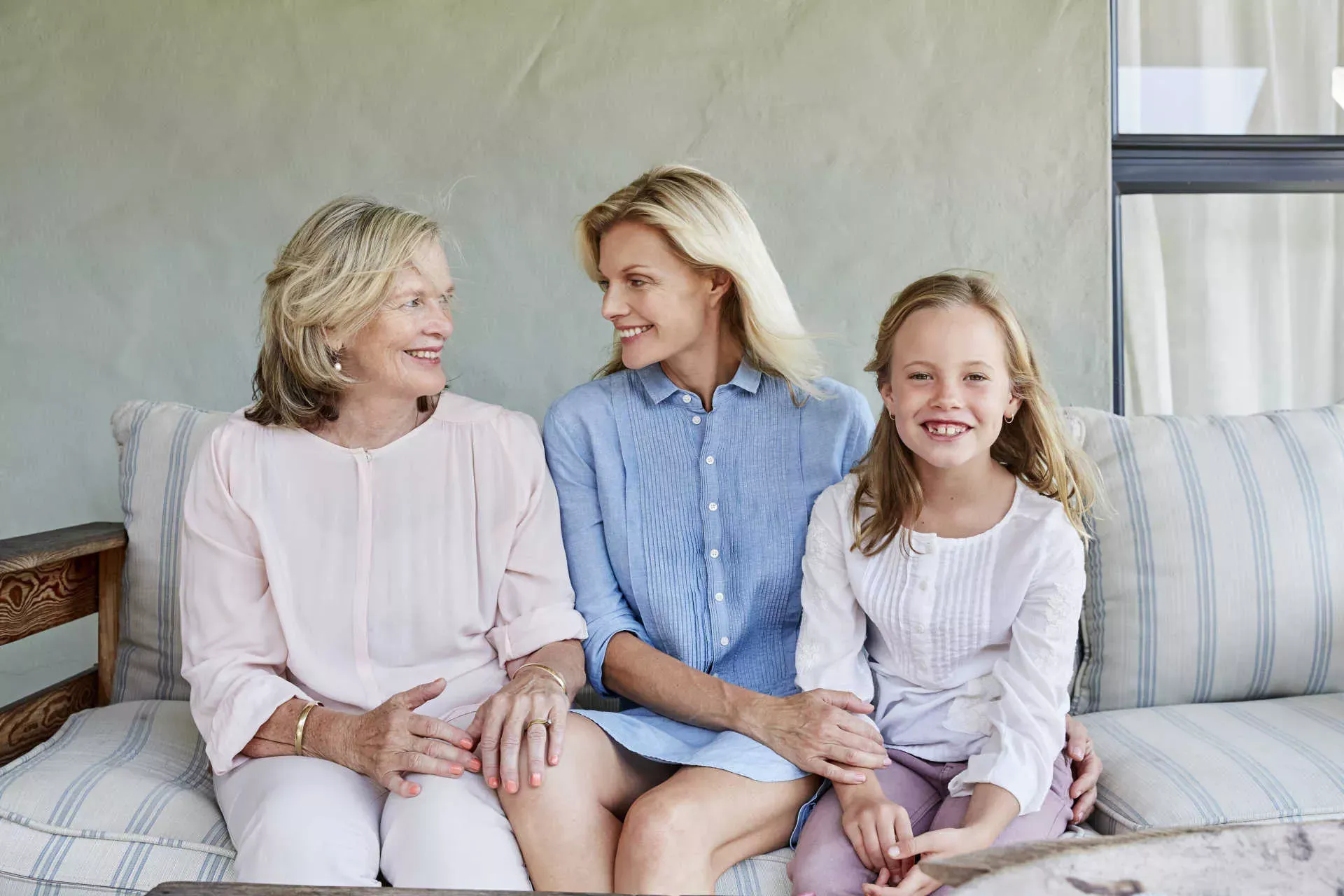 Mädchen sitzt mit Mutter und Großmutter auf einem Sofa auf der Terrasse. Bild: IMAGO / Westend61 / Martina Ferrari Mädchen sitzt mit Mutter und Großmutter auf einem Sofa auf der Terrasse. Bild: IMAGO / Westend61 / Martina Ferrari