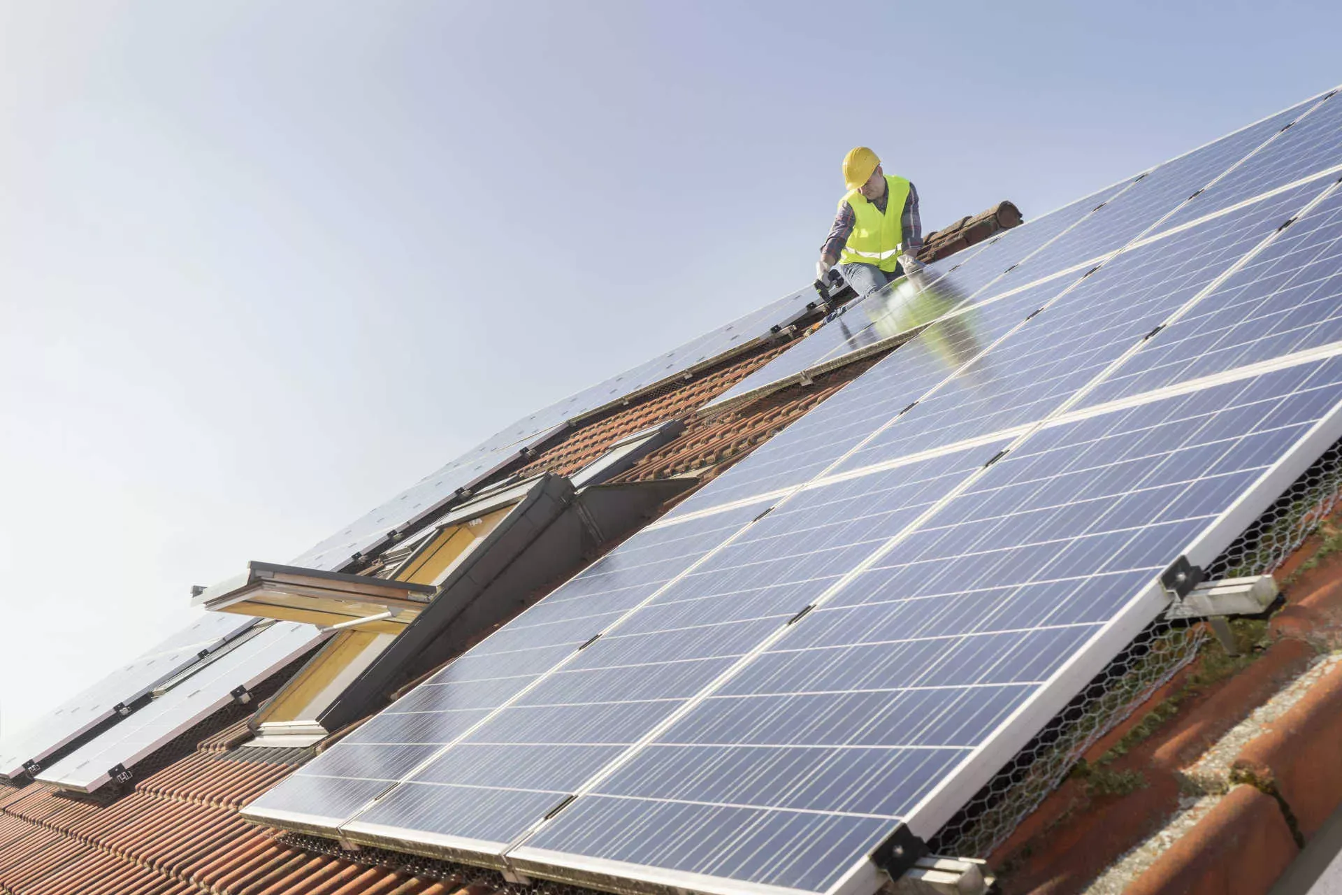 Arbeiter installiert Solarmodule auf Dach mit Fenster. Bild: IMAGO / Cavan Images / MITO images Arbeiter installiert Solarmodule auf Dach mit Fenster. Bild: IMAGO / Cavan Images / MITO images