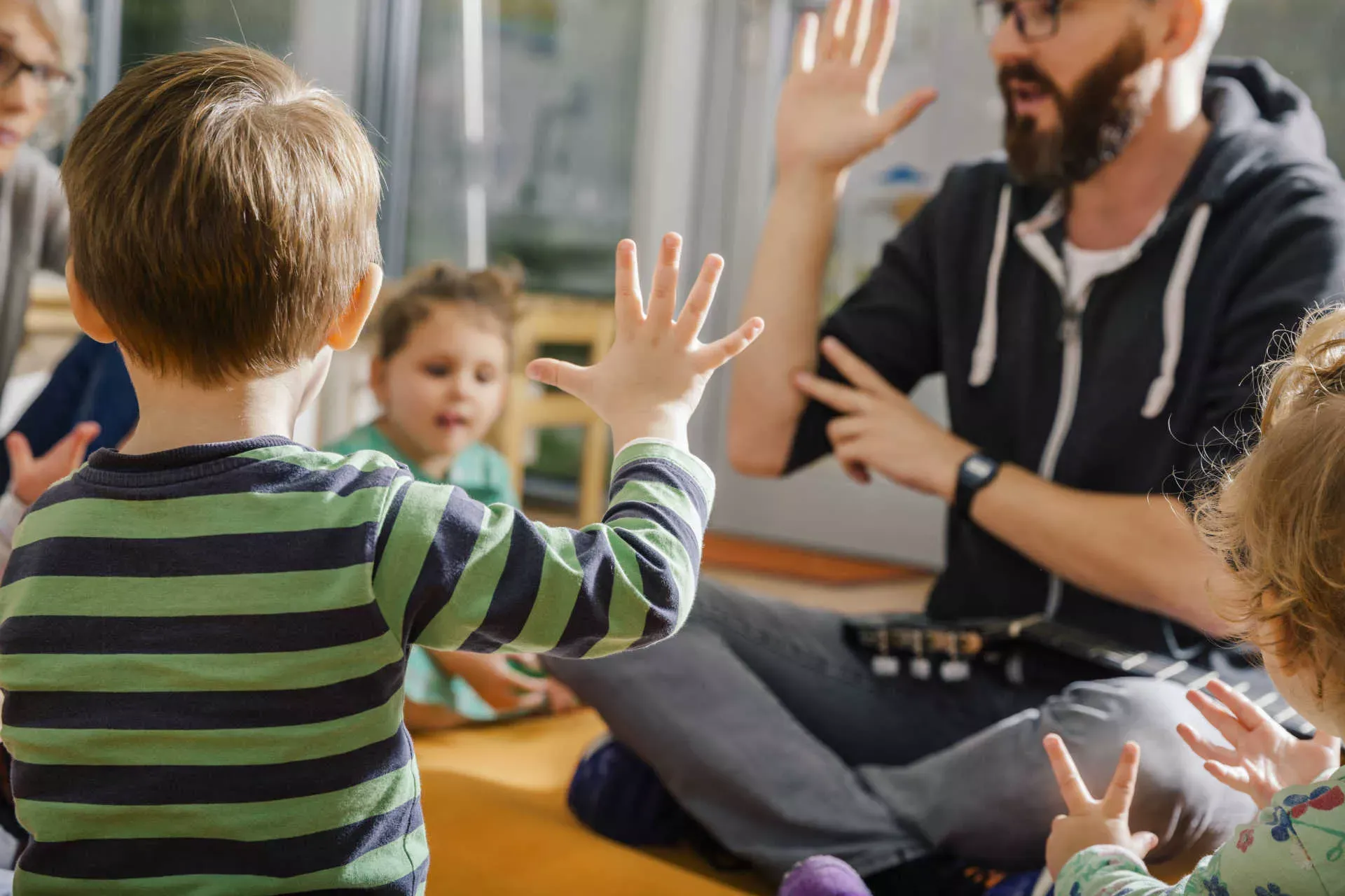 Erzieher spielt im Kreis mit Kindern in einer Kita. Bild: IMAGO / Westend61 / Mareen Fischinger Erzieher spielt im Kreis mit Kindern in einer Kita. Bild: IMAGO / Westend61 / Mareen Fischinger