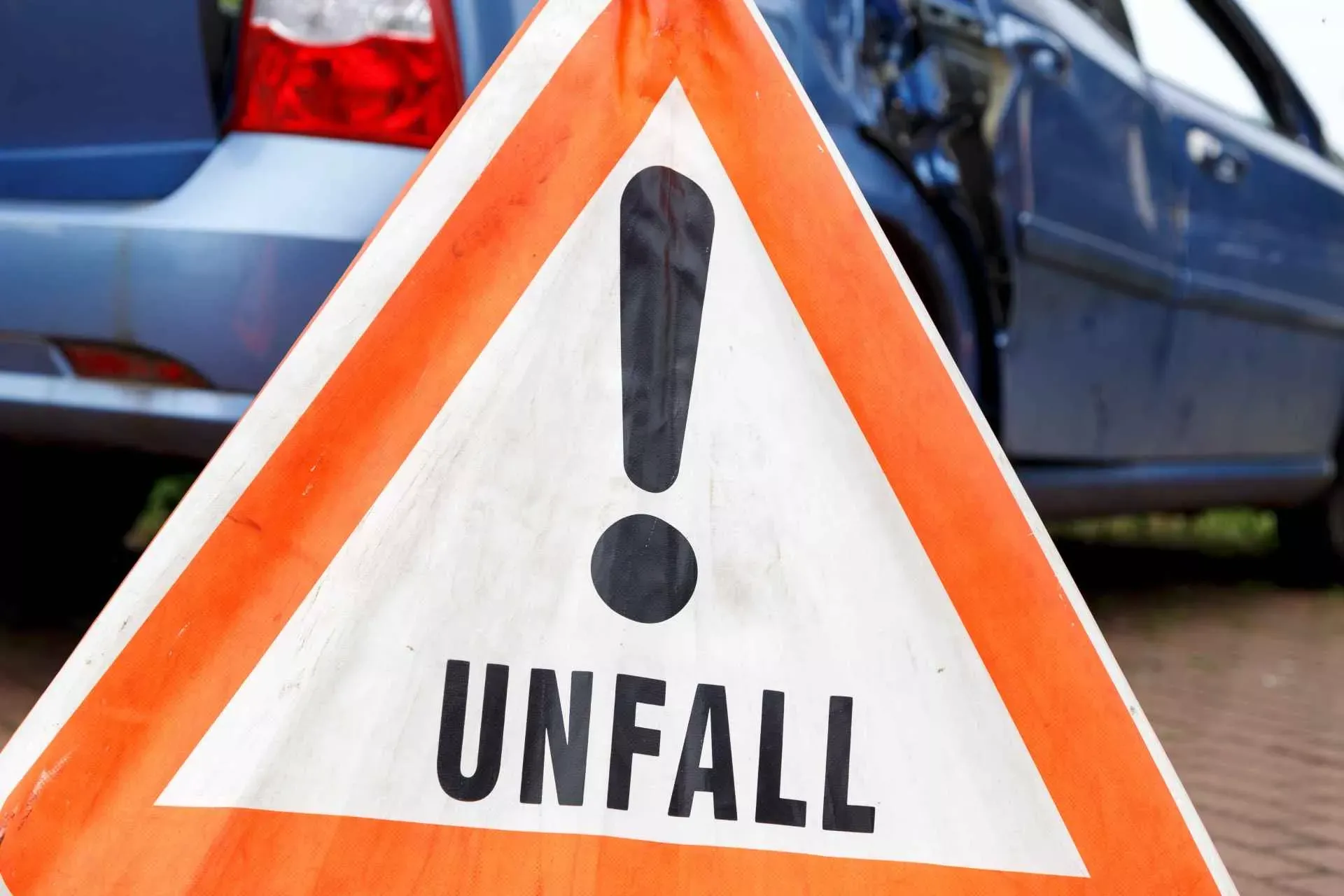 Unfallwarnschild vor einem beschädigten Auto. Bild: IMAGO / Panthermedia / juefraphoto Unfallwarnschild vor einem beschädigten Auto. Bild: IMAGO / Panthermedia / juefraphoto