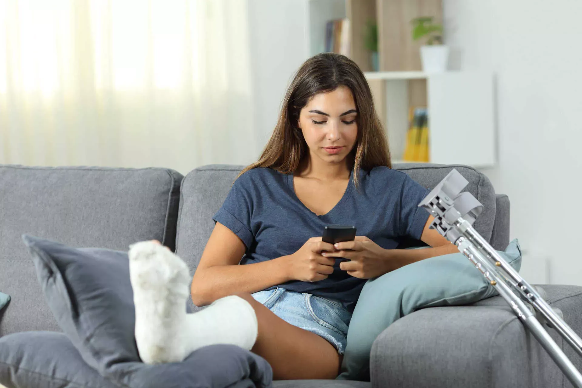 Junge Frau liegt mit Gipsbein auf dem Sofa und schaut auf ihr Smartphone. Bild: IMAGO / Panthermedia / Antonio Guillem Junge Frau liegt mit Gipsbein auf dem Sofa und schaut auf ihr Smartphone. Bild: IMAGO / Panthermedia / Antonio Guillem