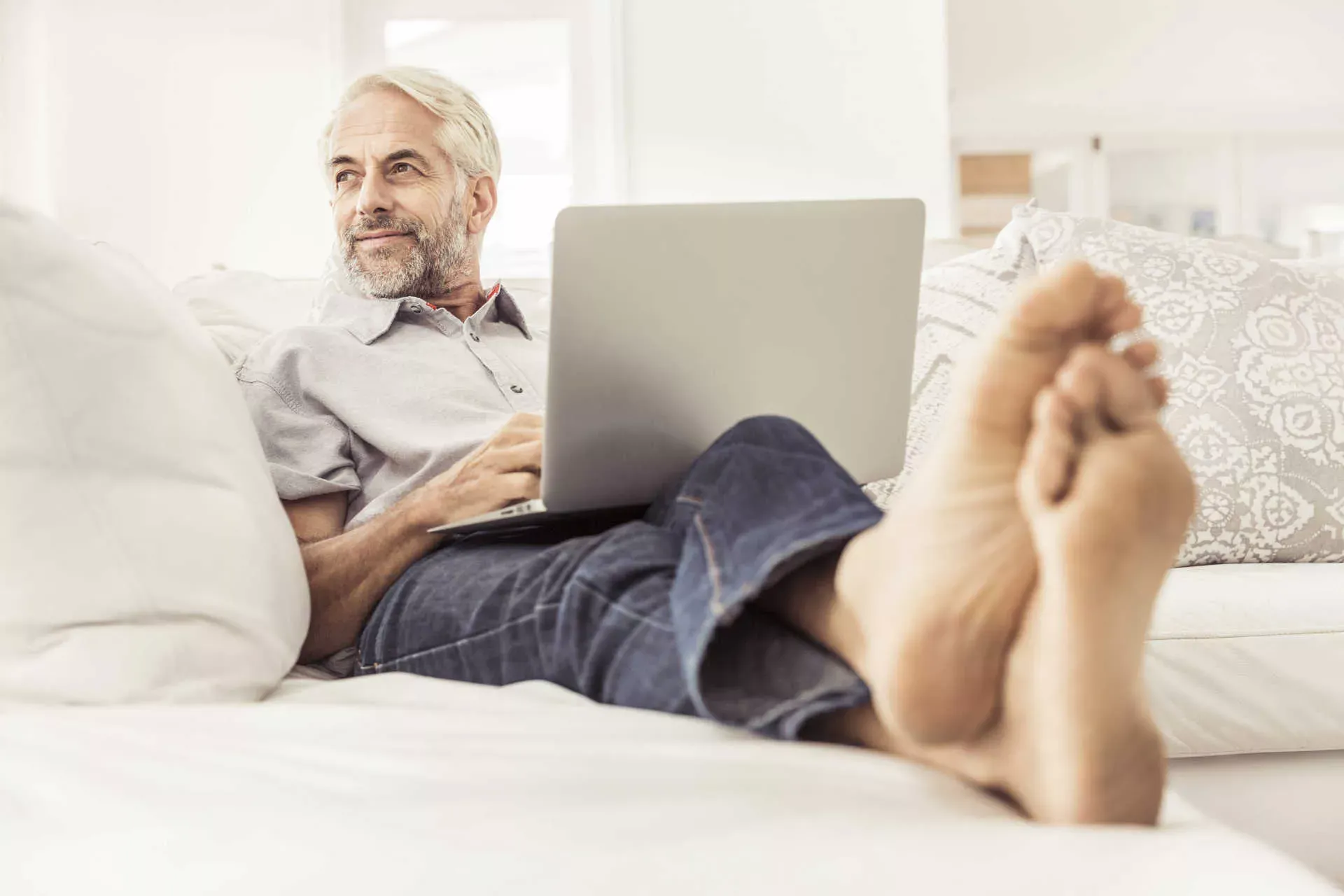 Älterer Mann liegt auch Sofa mit Notebook. Bild: IMAGO / Westend61 Älterer Mann liegt auch Sofa mit Notebook. Bild: IMAGO / Westend61
