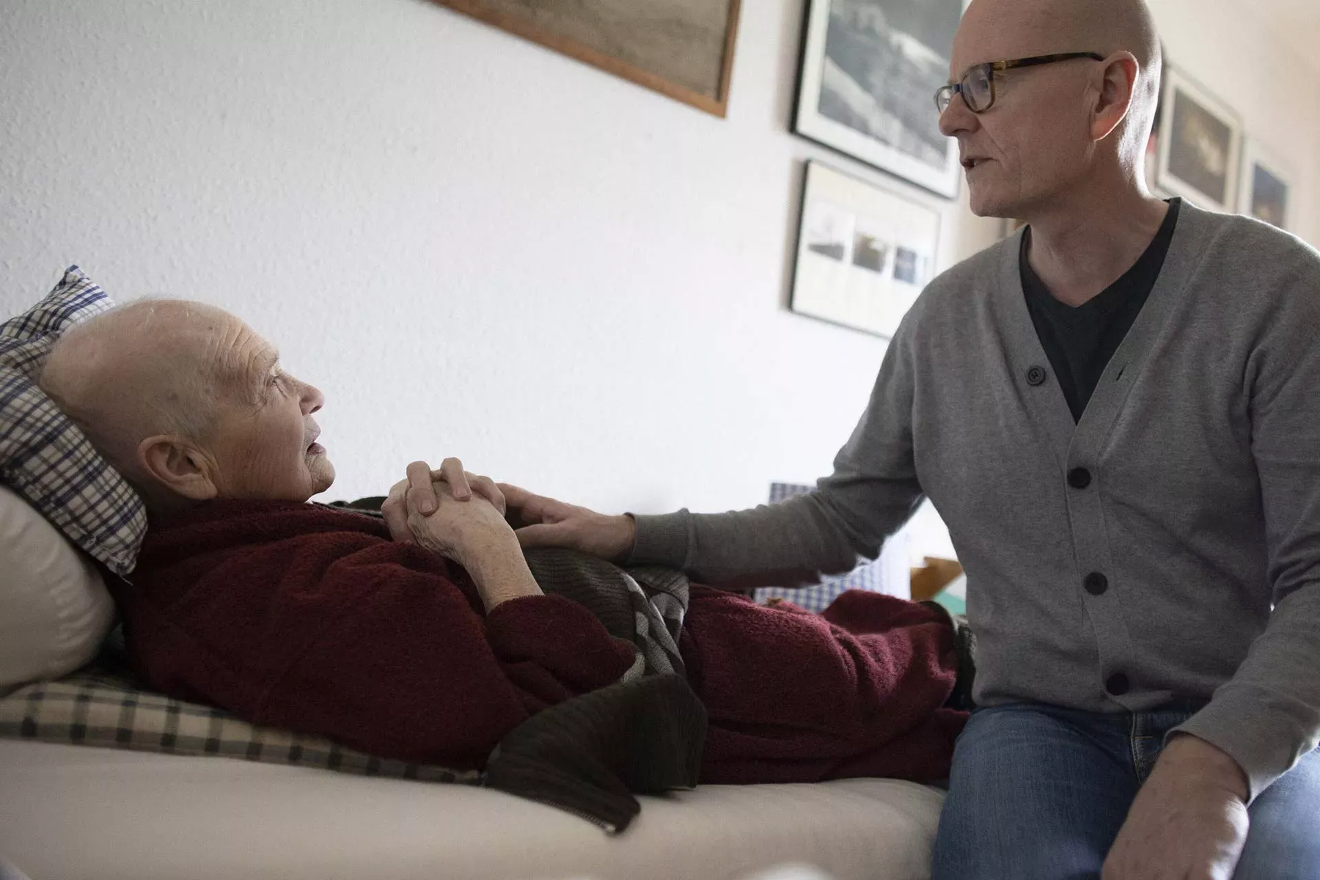 Sohn sitzt am Bett seiner pflegebedürftigen Mutter. Bild: IMAGO / photothek / Ute Grabowsky Sohn sitzt am Bett seiner pflegebedürftigen Mutter. Bild: IMAGO / photothek / Ute Grabowsky