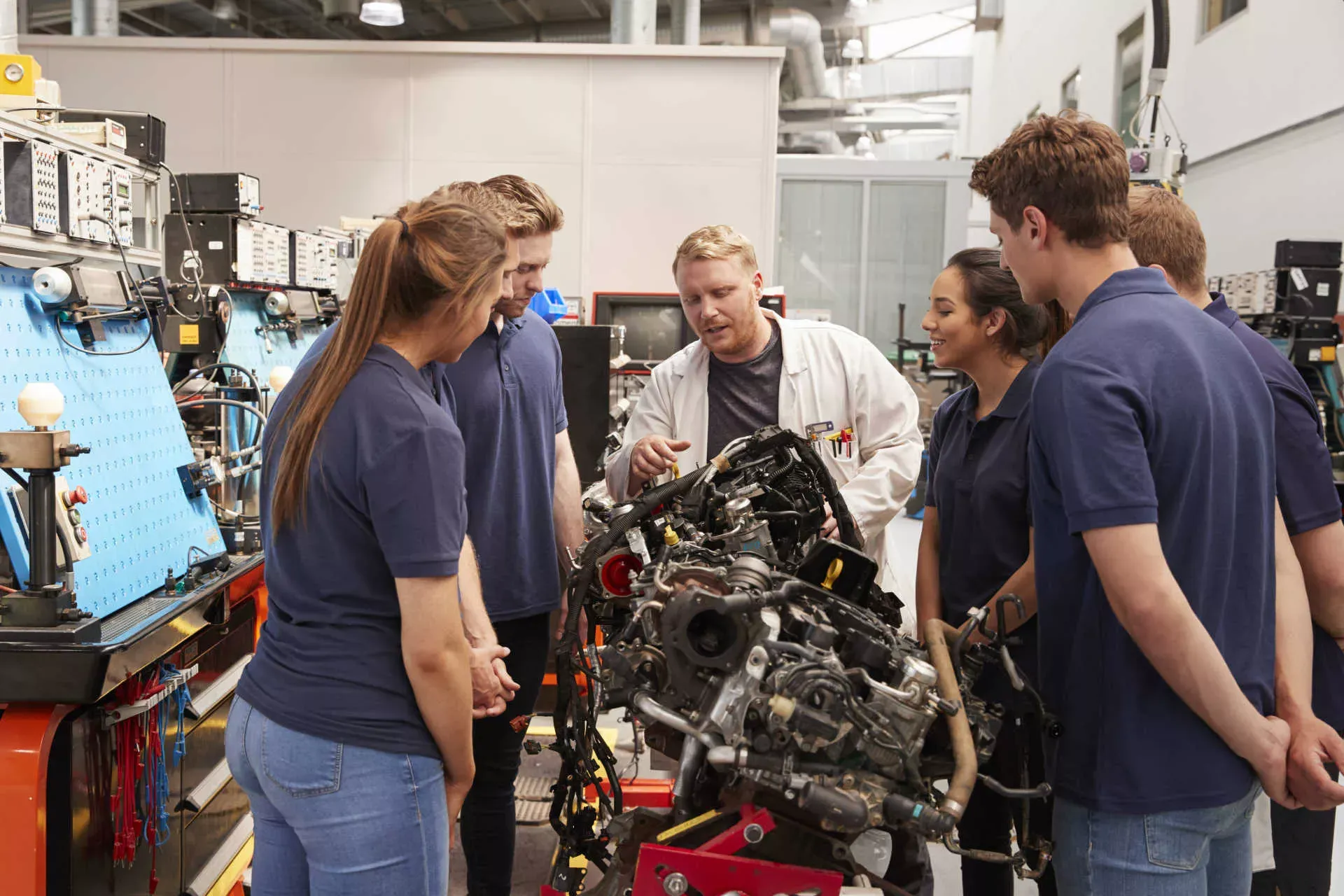 Gruppe Azubis steht um Ausbilder herum, der einen Motor erklärt. Bild: IMAGO / Shotshop / Monkeybusiness 2 Gruppe Azubis steht um Ausbilder herum, der einen Motor erklärt. Bild: IMAGO / Shotshop / Monkeybusiness 2