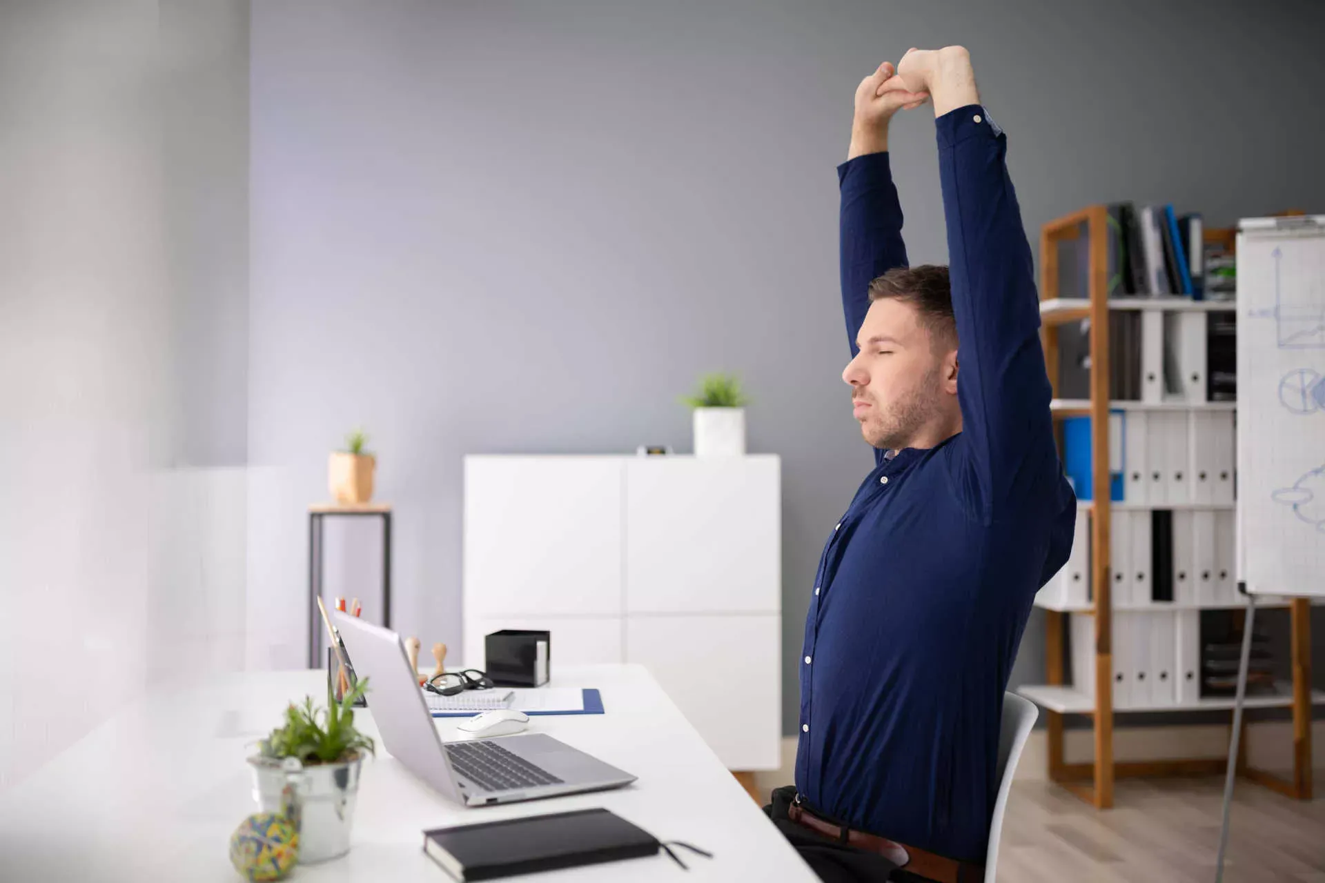 Mann im Büro macht Dehnübungen mit geschlossenen Augen. Bild: IMAGO / Panthermedia / Andrey Popov Mann im Büro macht Dehnübungen mit geschlossenen Augen. Bild: IMAGO / Panthermedia / Andrey Popov