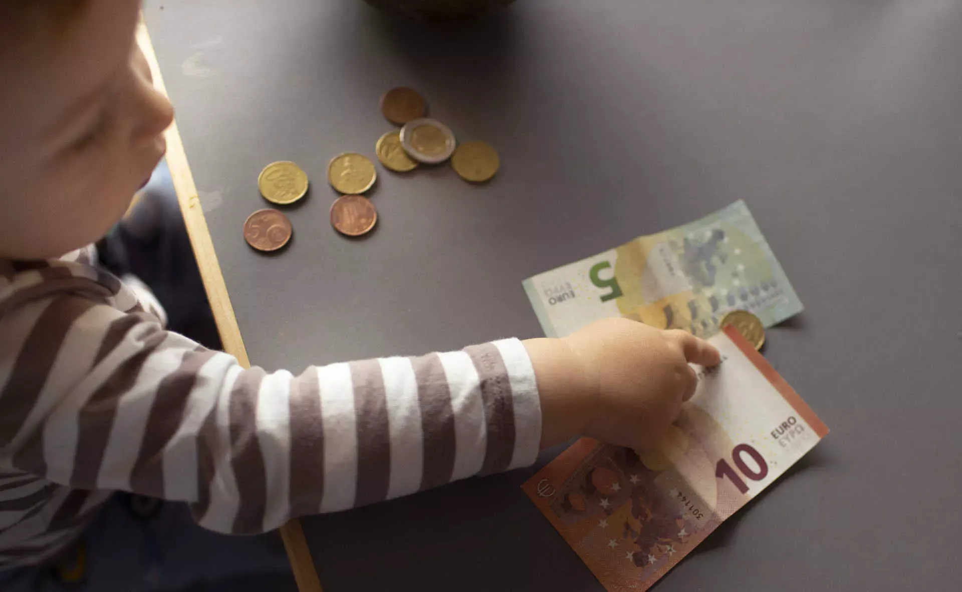 Kleines Kind mit Fünf- und Zehn-Euro-Scheinen. Bild: IMAGO / photothek / Ute Grabowsky Kleines Kind mit Fünf- und Zehn-Euro-Scheinen. Bild: IMAGO / photothek / Ute Grabowsky