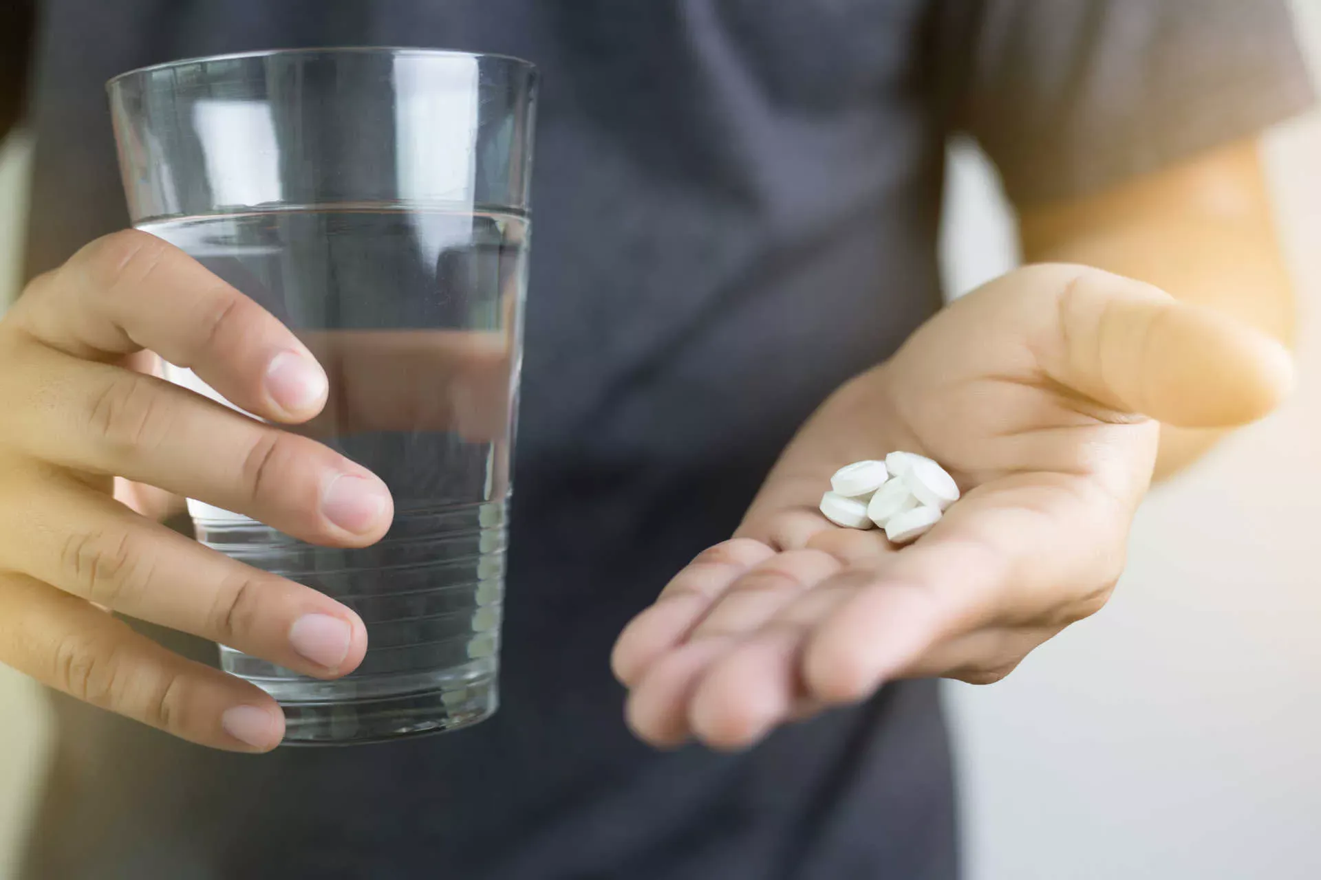Mann hält Tabletten in der einen Hand, Glas Wasser in der anderen. Bild: IMAGO / agefotostock /duiwoy55 Mann hält Tabletten in der einen Hand, Glas Wasser in der anderen. Bild: IMAGO / agefotostock /duiwoy55