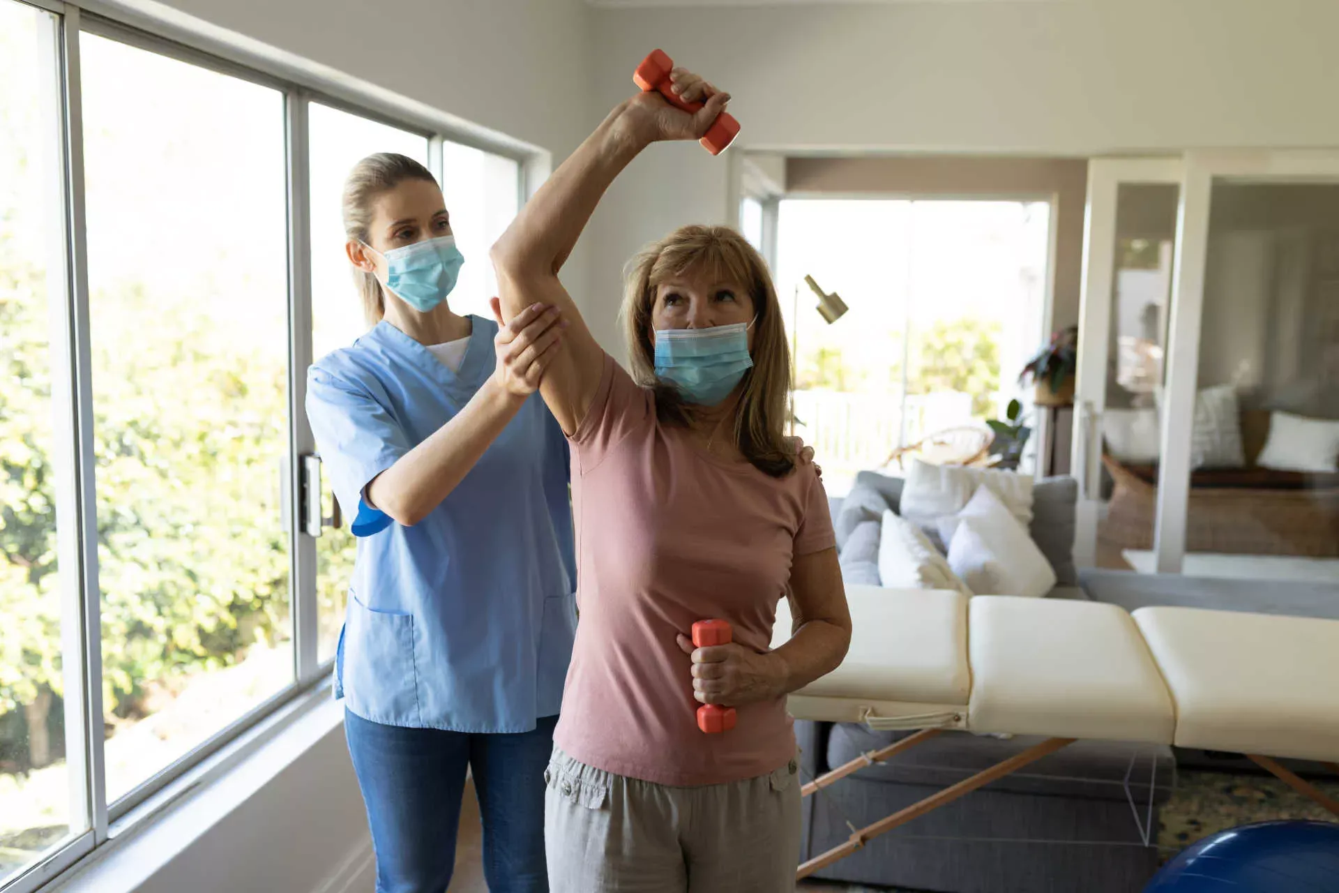 Ältere Rehapatientin macht Hantelübungen mit Physiotherapeutin, beide tragen Corona-Schutzmasken. Bild: IMAGO / Wavebreak Media Ltd Ältere Rehapatientin macht Hantelübungen mit Physiotherapeutin, beide tragen Corona-Schutzmasken. Bild: IMAGO / Wavebreak Media Ltd