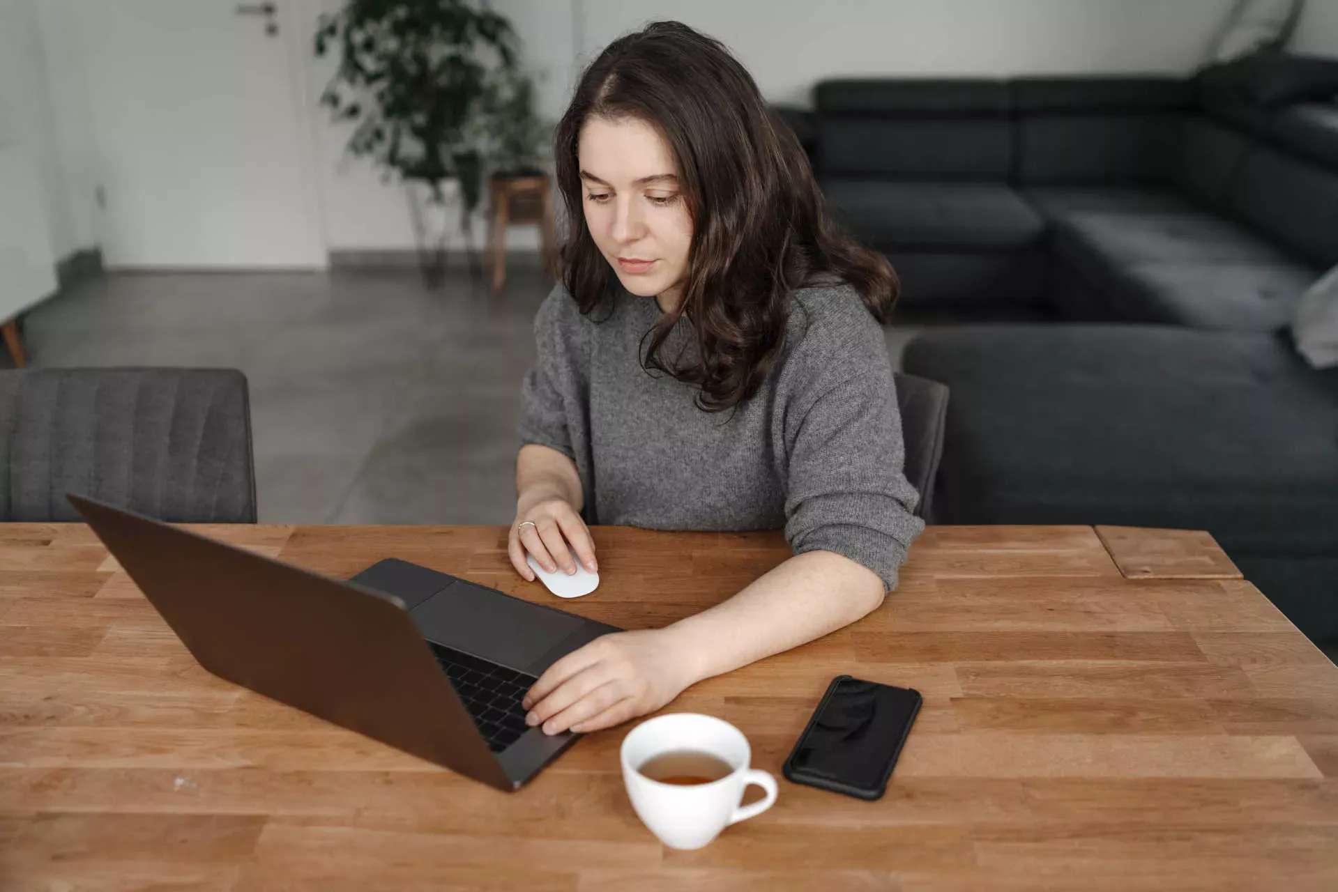 Junge Frau bedient Maus und Tastatur an einem Notebook, daneben eine Tasse und ein Smartphone. Bild: IMAGO / Westend61 / Oxana Guryanova Junge Frau bedient Maus und Tastatur an einem Notebook, daneben eine Tasse und ein Smartphone. Bild: IMAGO / Westend61 / Oxana Guryanova