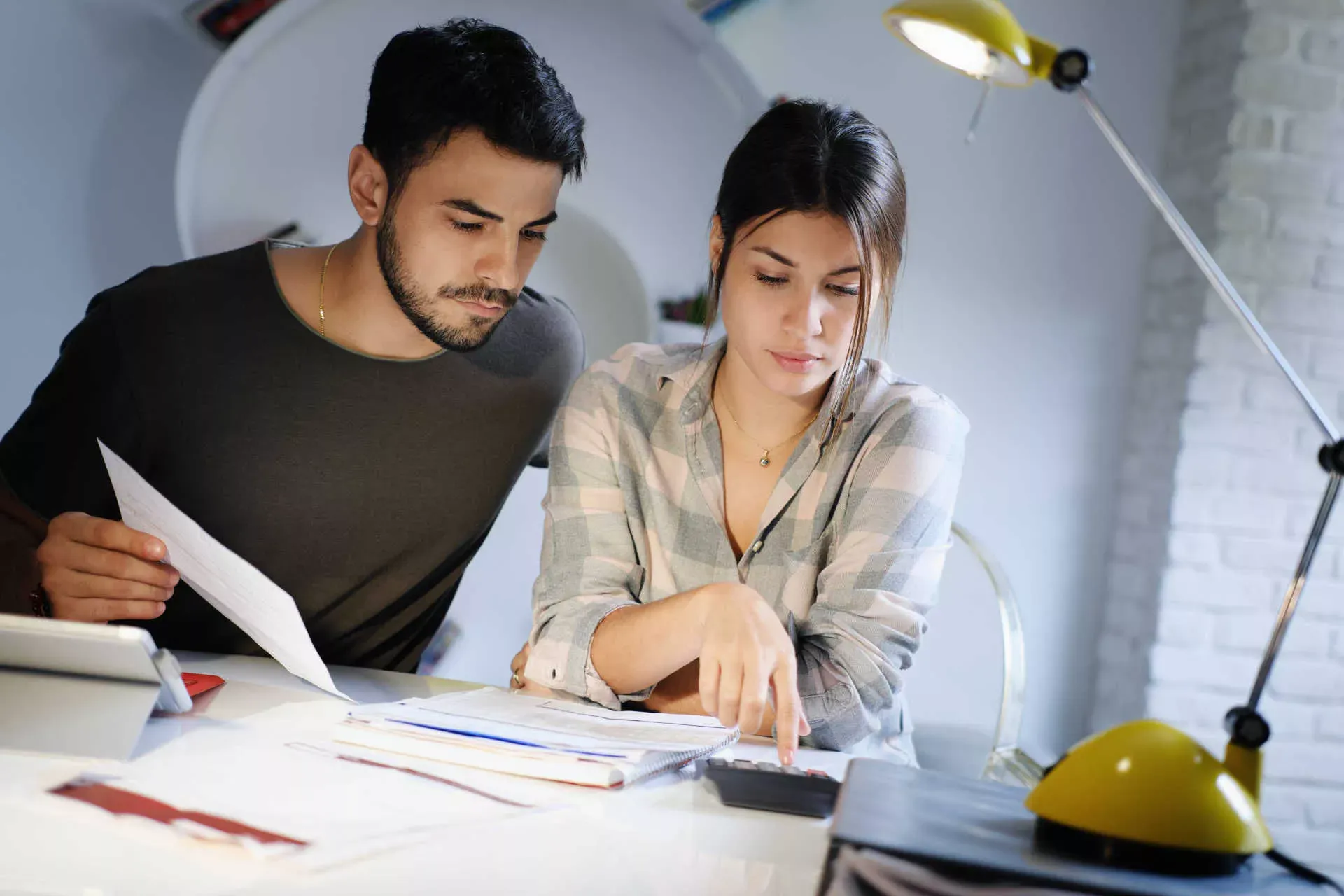 Junges Paar zuhause am Schreibtisch prüft Kosten mit Taschenrechner. Bild: IMAGO / Shotshop / DC_2 Junges Paar zuhause am Schreibtisch prüft Kosten mit Taschenrechner. Bild: IMAGO / Shotshop / DC_2