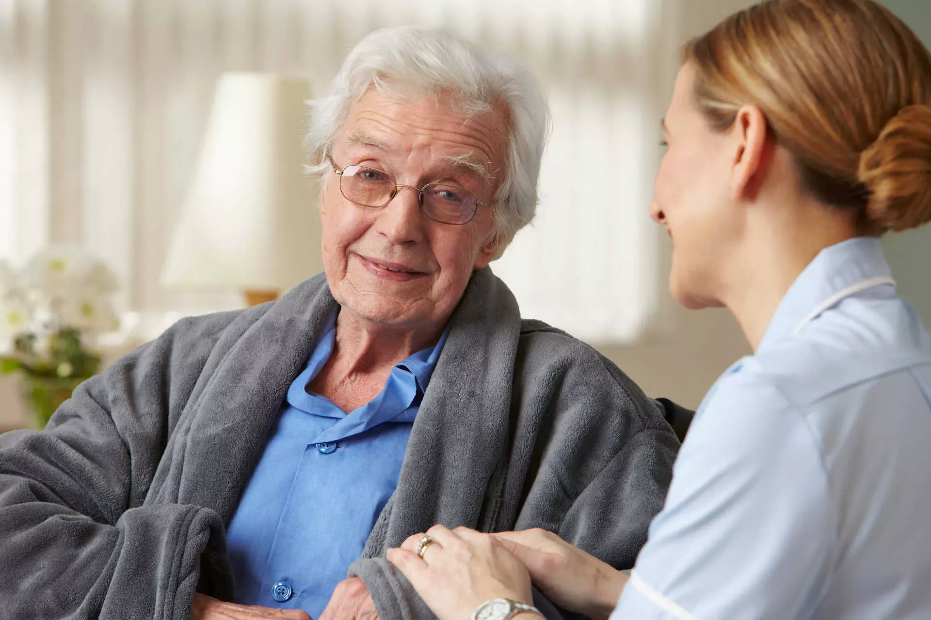 Seniorin im Bademantel und junge Pflegerin im Heim. Bild: IMAGO / Image Source / Nick White Seniorin im Bademantel und junge Pflegerin im Heim. Bild: IMAGO / Image Source / Nick White