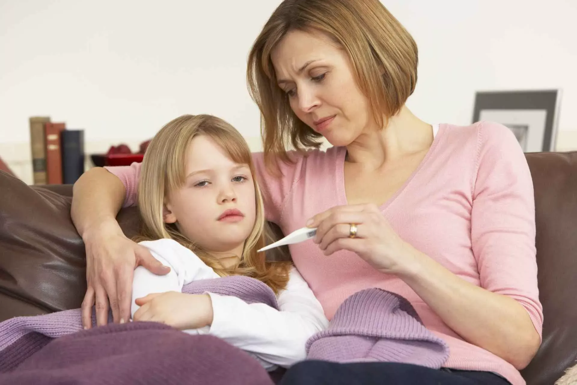 Eine Frau misst bei einem kleinen Mädchen Fieber. Bild: IMAGO / Shotshop Eine Frau misst bei einem kleinen Mädchen Fieber. Bild: IMAGO / Shotshop