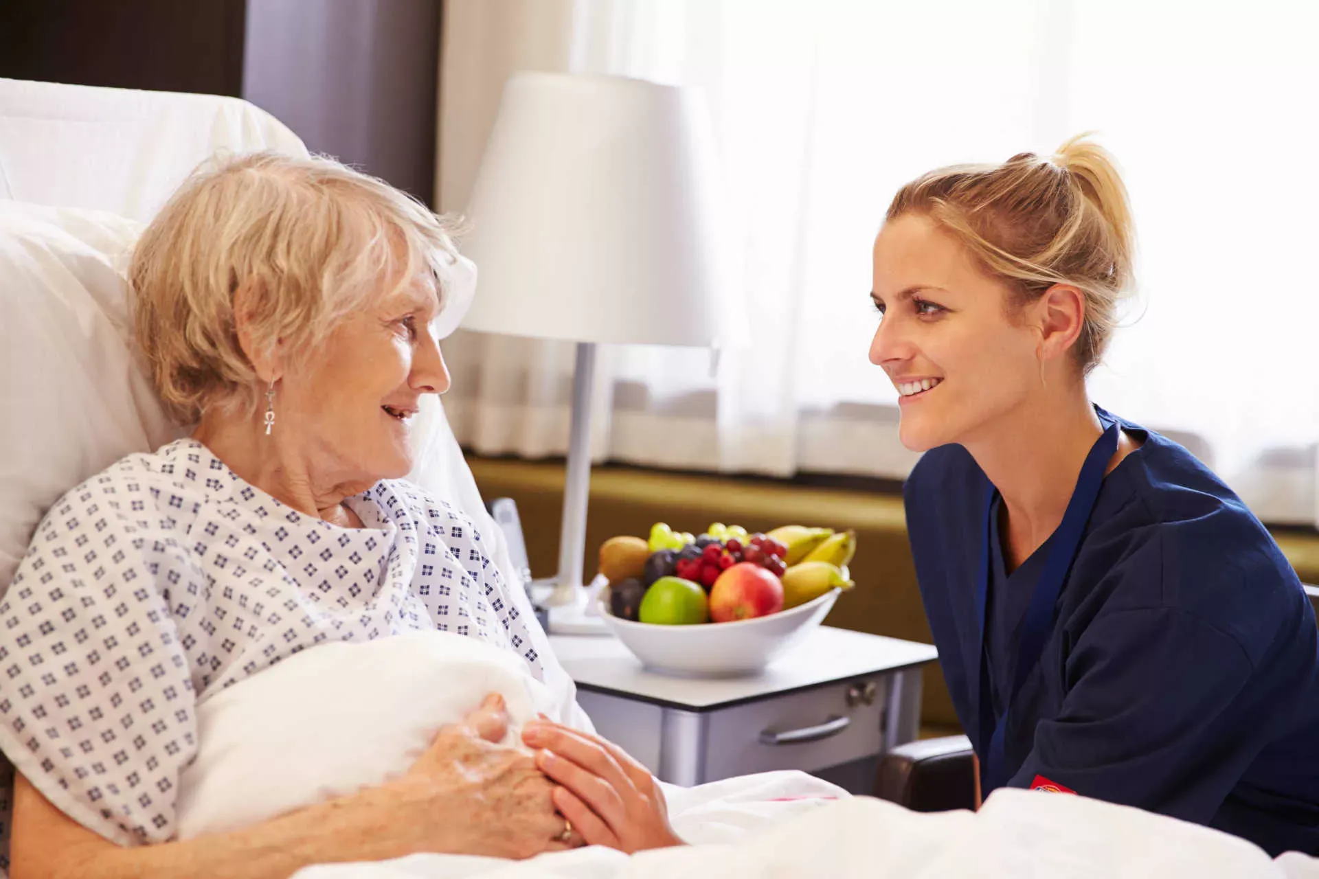 Pflegefachkraft sitzt am Bett einer Seniorin im Pflegeheim und hält ihre Hand. Bild: IMAGO / Shotshop / Monkey Business 2 Pflegefachkraft sitzt am Bett einer Seniorin im Pflegeheim und hält ihre Hand. Bild: IMAGO / Shotshop / Monkey Business 2