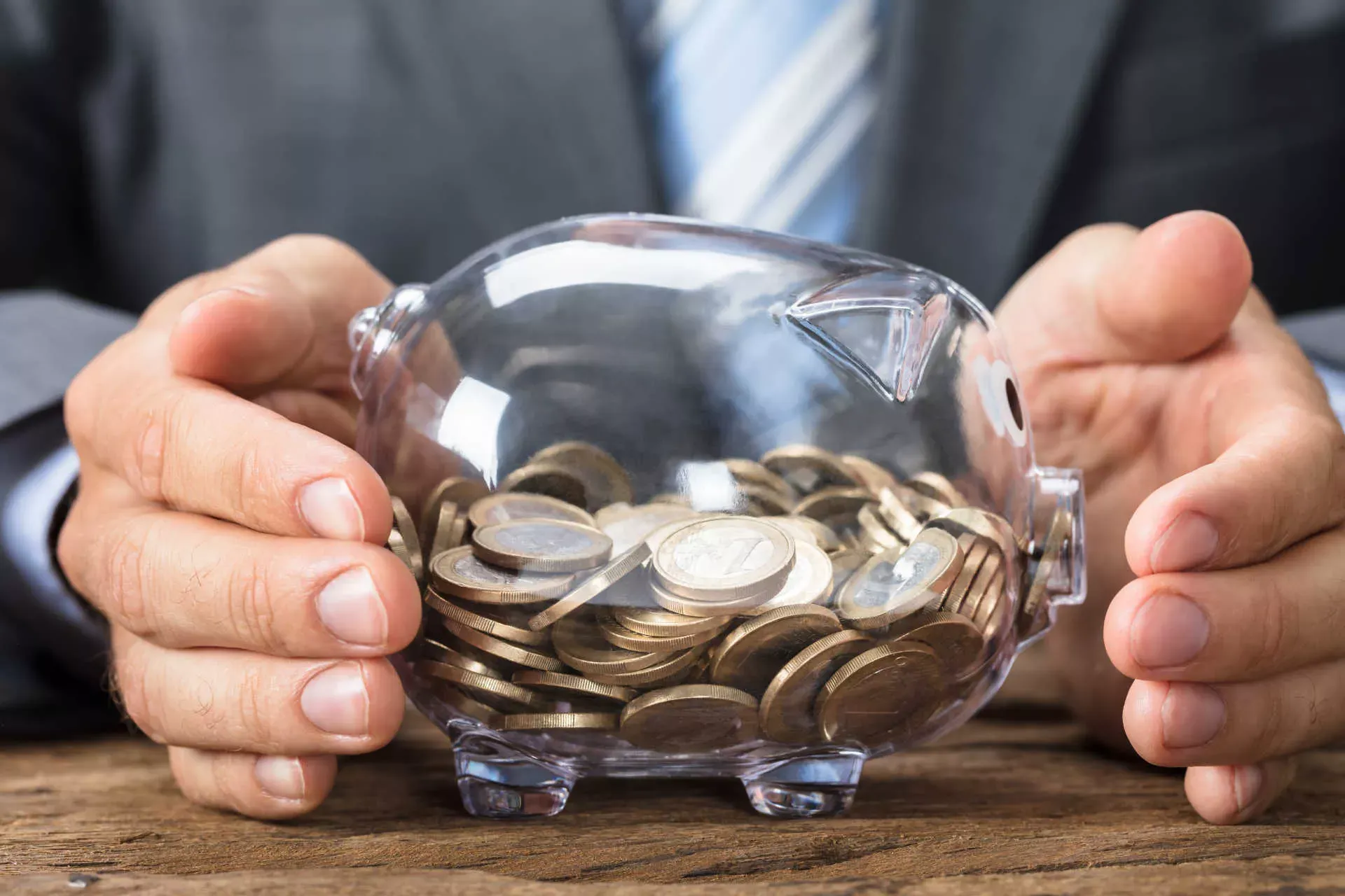 Businessmann umfasst ein transparentes Sparschwein mit 1-Euro-Münzen. Bild: IMAGO / Panthermedia / Andriy Popov Businessmann umfasst ein transparentes Sparschwein mit 1-Euro-Münzen. Bild: IMAGO / Panthermedia / Andriy Popov