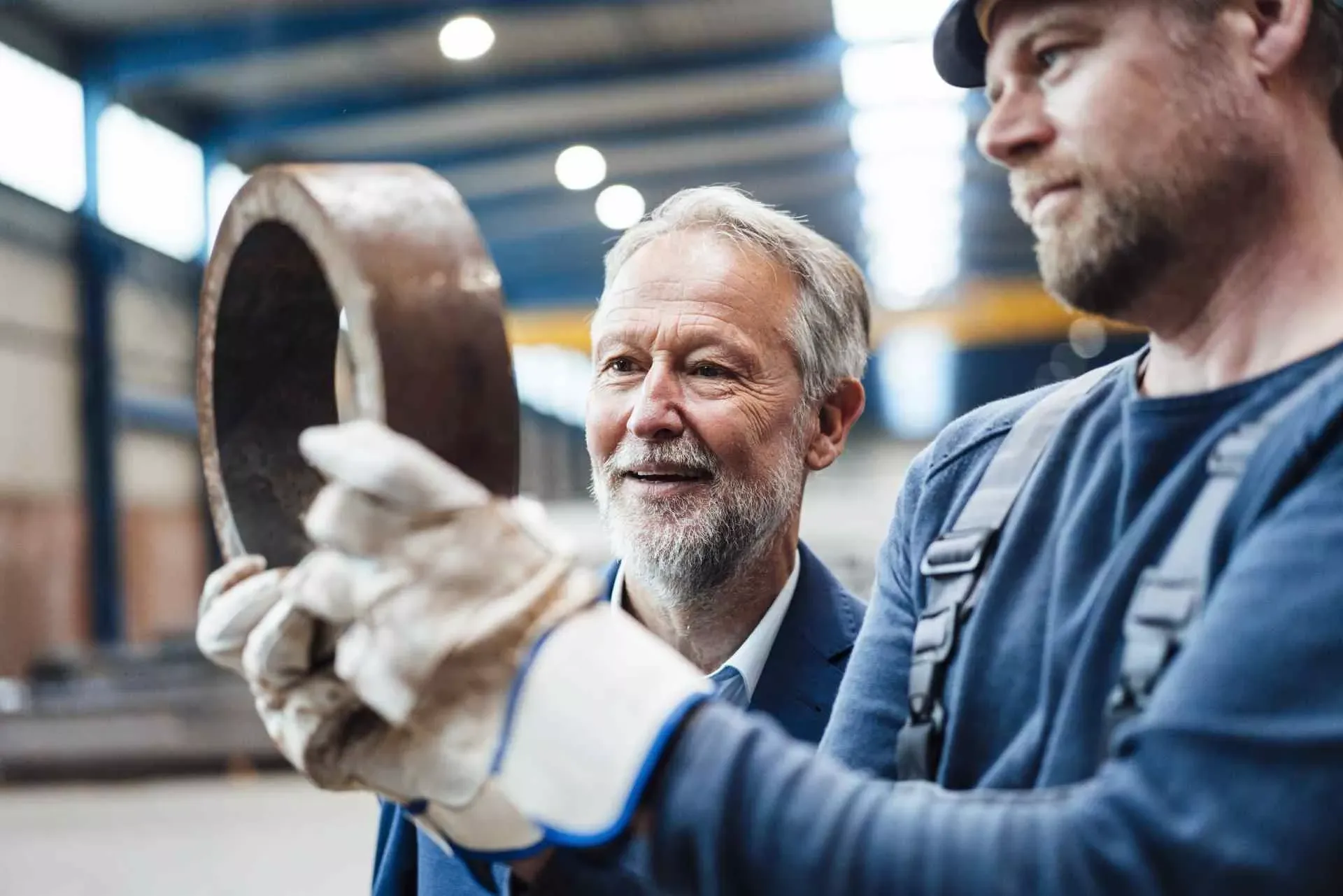 Älterer Arbeiter mit jüngerem Kollege in einer Fabrikhalle. Bild: IMAGO / Westend61 Älterer Arbeiter mit jüngerem Kollege in einer Fabrikhalle. Bild: IMAGO / Westend61