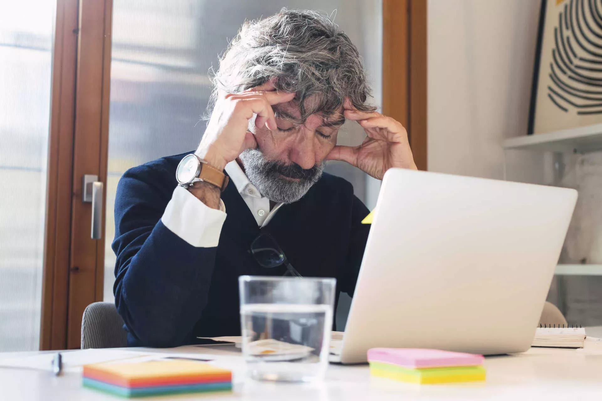 Älterer Mann sitzt erschöpft mit geschlossenen Augen vor seinem Notebook. Bild: IMAGO / Westend61 / NOVELLIMAGE Älterer Mann sitzt erschöpft mit geschlossenen Augen vor seinem Notebook. Bild: IMAGO / Westend61 / NOVELLIMAGE