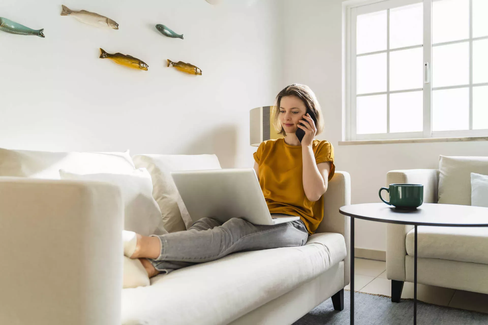 Junge Frau liegt mit Notebook auf dem Sofa und telefoniert mit Smartphone. Bild: IMAGO / Westend61 / Daniel Ingold Junge Frau liegt mit Notebook auf dem Sofa und telefoniert mit Smartphone. Bild: IMAGO / Westend61 / Daniel Ingold