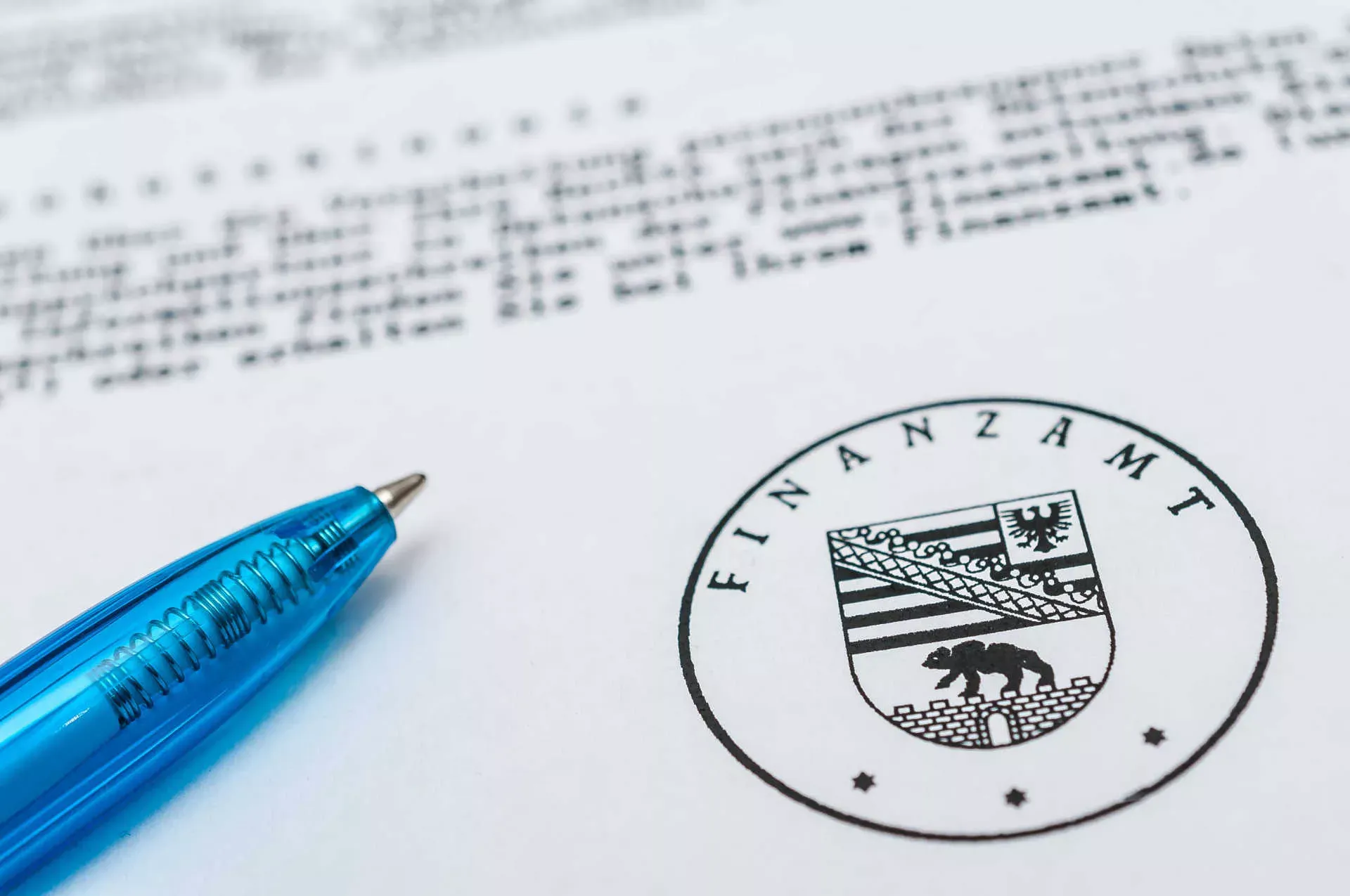 Steuerbescheid, Ausschnitt mit Stempel Finanzamt, darüber liegt ein blauer Kugelschreiber. Bild: IMAGO / Zoonar.com / stockfotos-mg Steuerbescheid, Ausschnitt mit Stempel Finanzamt, darüber liegt ein blauer Kugelschreiber. Bild: IMAGO / Zoonar.com / stockfotos-mg