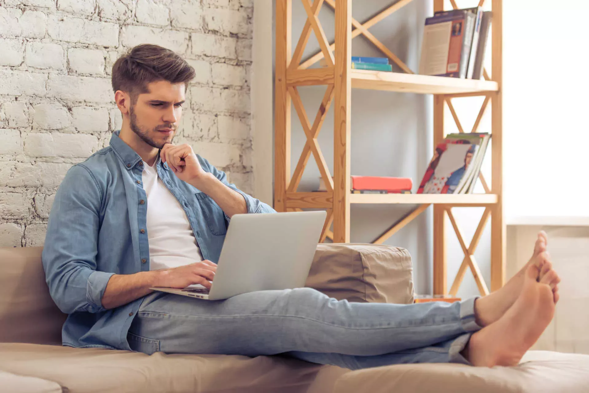 Junger Mann auf dem Sofa schaut nachdenklich auf sein Notebook. Bild: IMAGO / agefotostock / George Rudy Junger Mann auf dem Sofa schaut nachdenklich auf sein Notebook. Bild: IMAGO / agefotostock / George Rudy