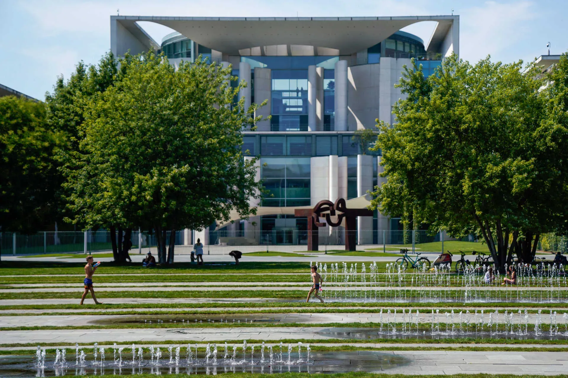 Bundeskanzleramt in Berlin im Sommer mit spielenden Kindern im Vordergrund an den Springbrunnen. Bild: IMAGO / Fotostand / Reuhl Bundeskanzleramt in Berlin im Sommer mit spielenden Kindern im Vordergrund an den Springbrunnen. Bild: IMAGO / Fotostand / Reuhl