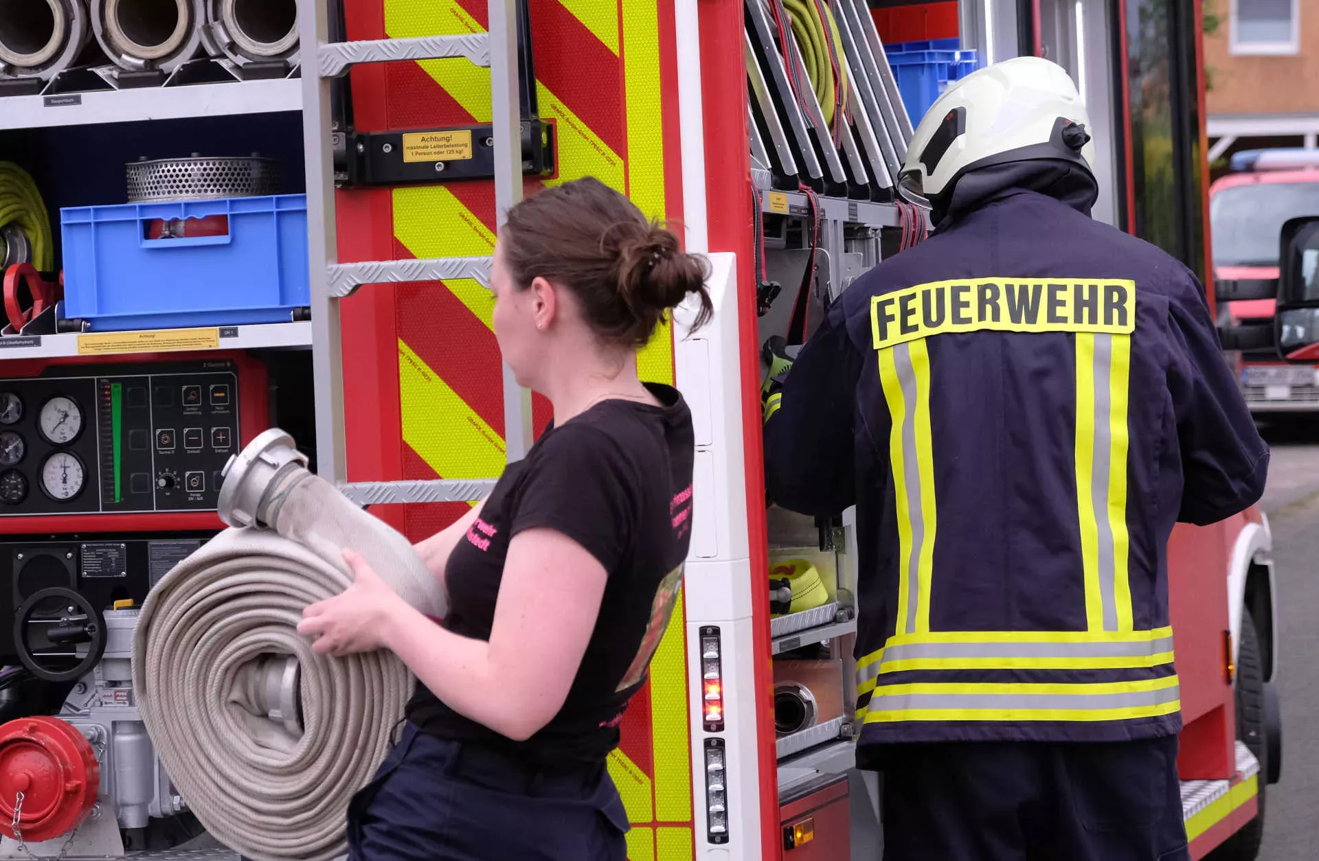Einsatz Feuerwehrauto, Frau trägt Feuerwehrschlauch. Bild: IMAGO / Martin Wagner Einsatz Feuerwehrauto, Frau trägt Feuerwehrschlauch. Bild: IMAGO / Martin Wagner