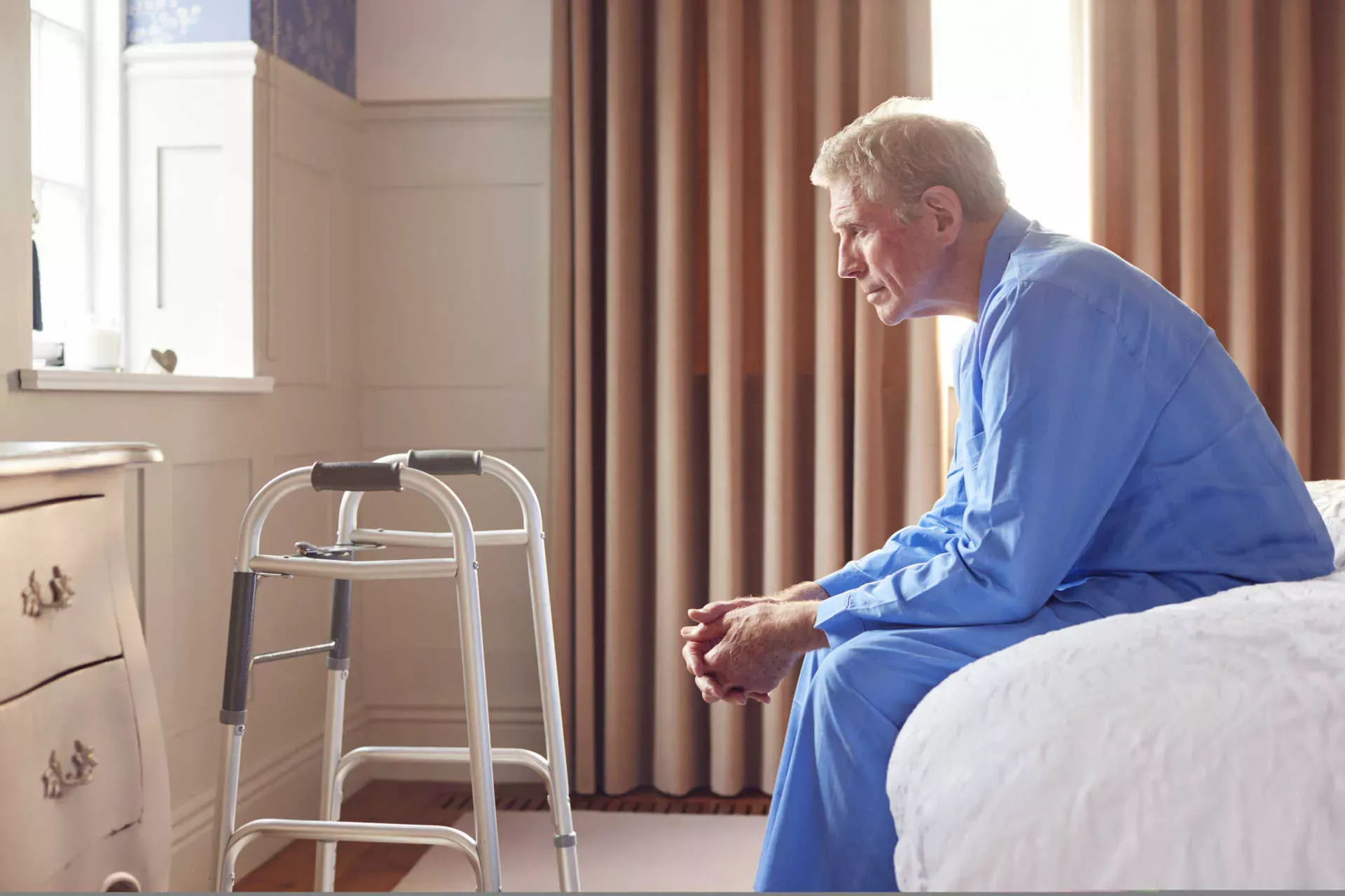 Deprimierter Senior sitzt auf dem Bettrand, vor sich eine Gehhilfe. Bild: IMAGO / Shotshop / Monkey Business 2 Deprimierter Senior sitzt auf dem Bettrand, vor sich eine Gehhilfe. Bild: IMAGO / Shotshop / Monkey Business 2