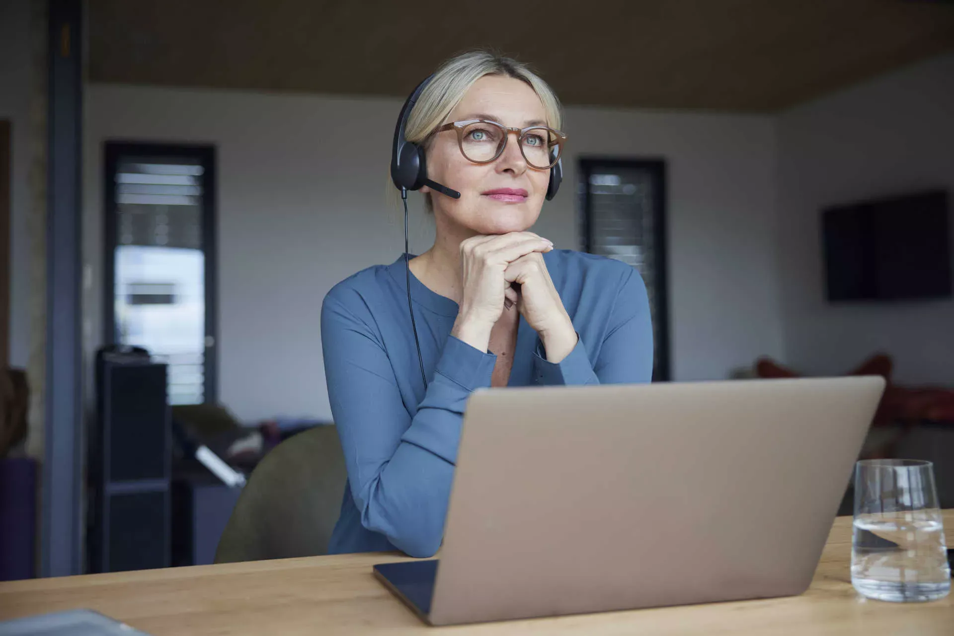 Frau mit Headset sitzt vor ihrem Laptop, schaut in die Ferne und hört zu. Bild: IMAGO / Westend61 / Rainer Berg Frau mit Headset sitzt vor ihrem Laptop, schaut in die Ferne und hört zu. Bild: IMAGO / Westend61 / Rainer Berg