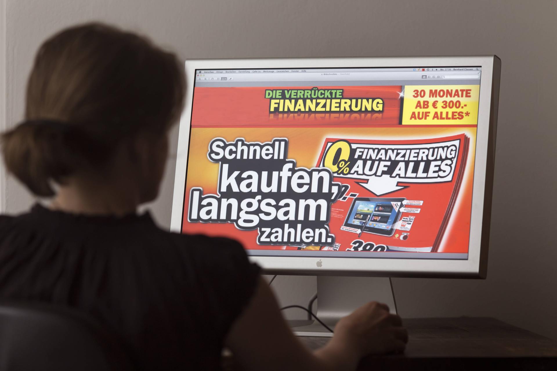 Frau betrachtet Bildschirm mit Werbung für Null-Prozent-Finanzierung eines Elektromarktes Frau betrachtet Bildschirm mit Werbung für Null-Prozent-Finanzierung eines Elektromarktes