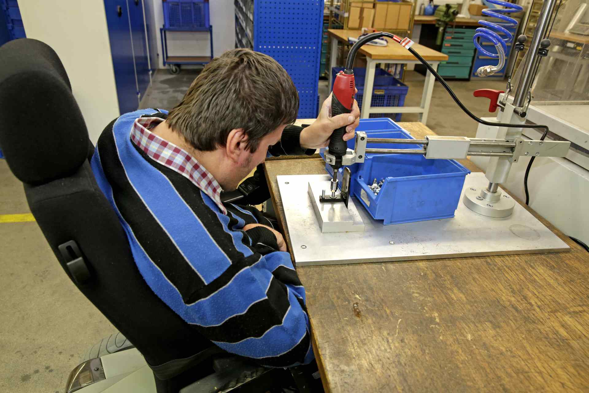 Geistig und körperlich behinderter Mann bei der Arbeit an einer Werkbank Geistig und körperlich behinderter Mann bei der Arbeit an einer Werkbank