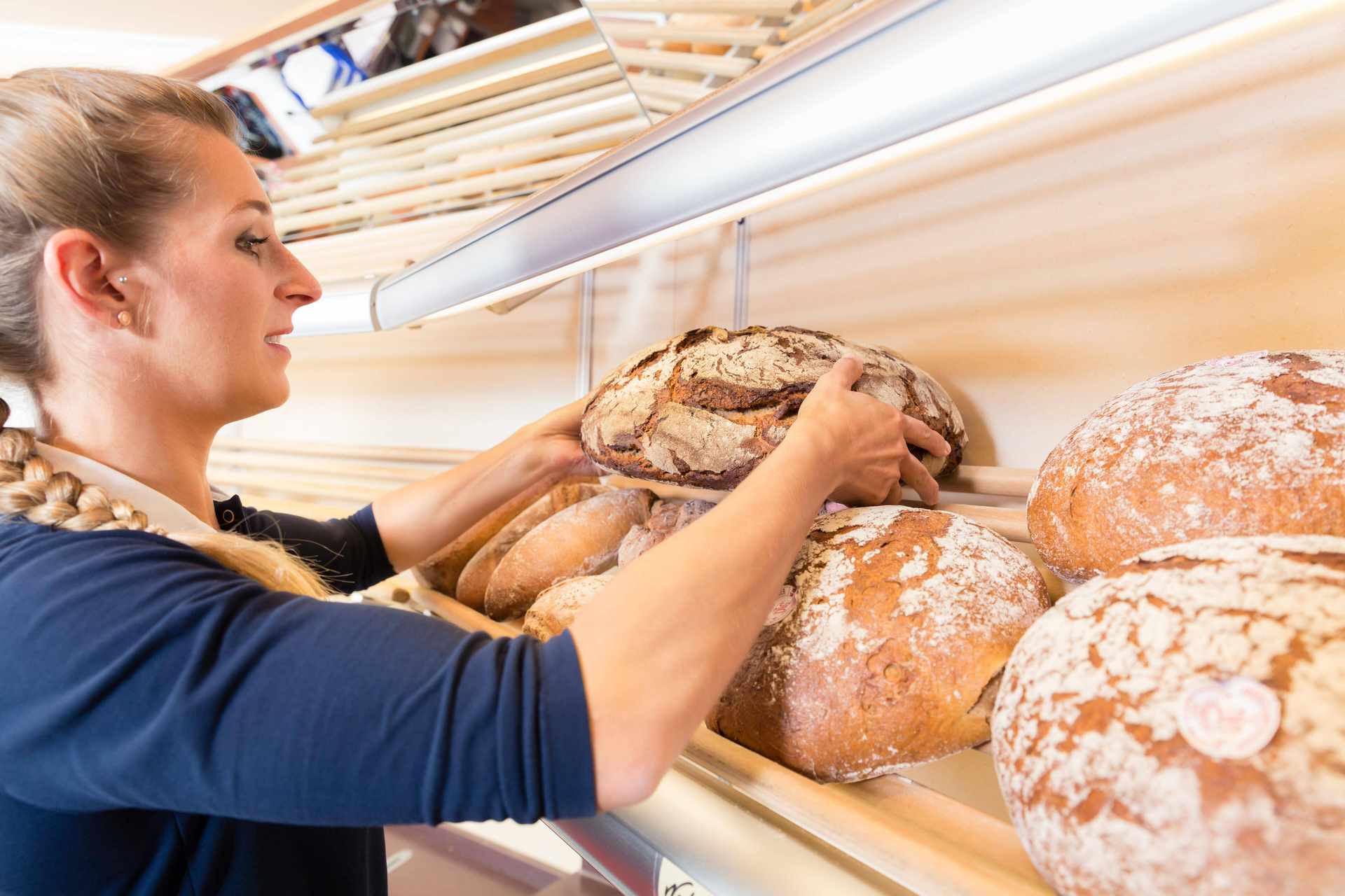 Bächereiverkäuferin räumt Brote ins Regal Bächereiverkäuferin räumt Brote ins Regal