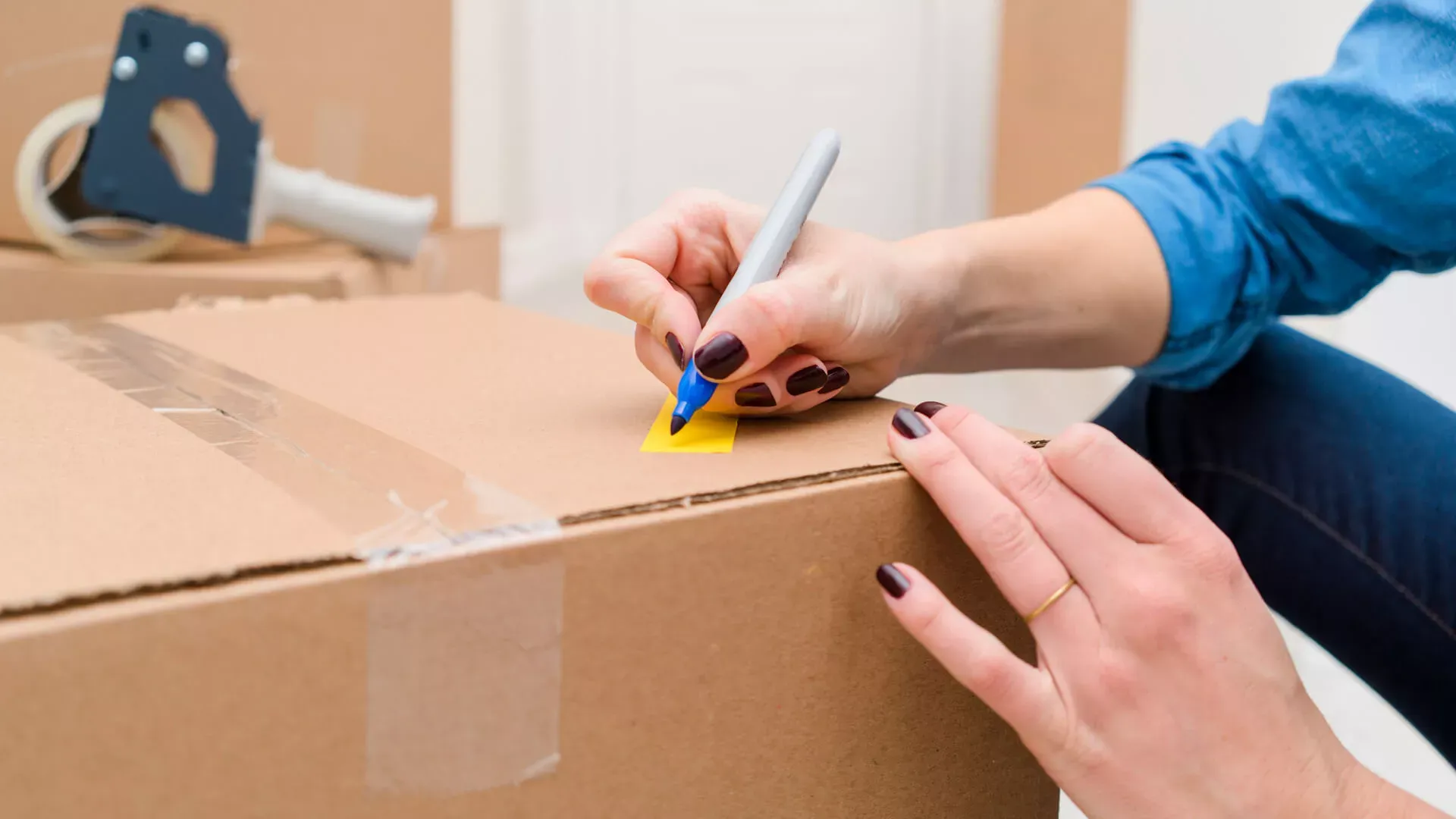 Frauenhand beschriftet einen Umzugskarton. Bildnachweis: stocksy.com © Suzanne Clements Frauenhand beschriftet einen Umzugskarton. Bildnachweis: stocksy.com © Suzanne Clements