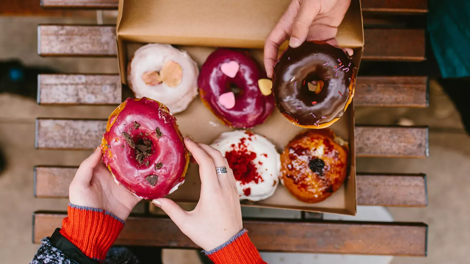 Zwei Hände greifen nach mehreren Donuts in einer Schachtel. Bildnachweis: Stocksy © Kristen Curette Hines Zwei Hände greifen nach mehreren Donuts in einer Schachtel. Bildnachweis: Stocksy © Kristen Curette Hines