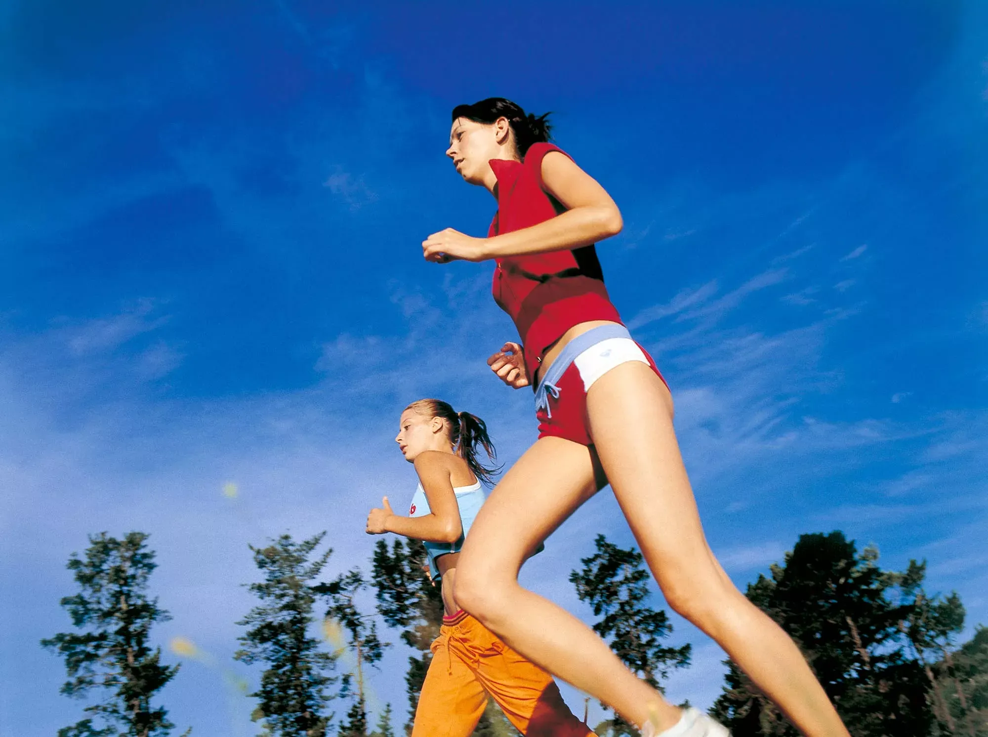 Zwei Frauen joggen vor blauem Himmel. Zwei Frauen joggen vor blauem Himmel.
