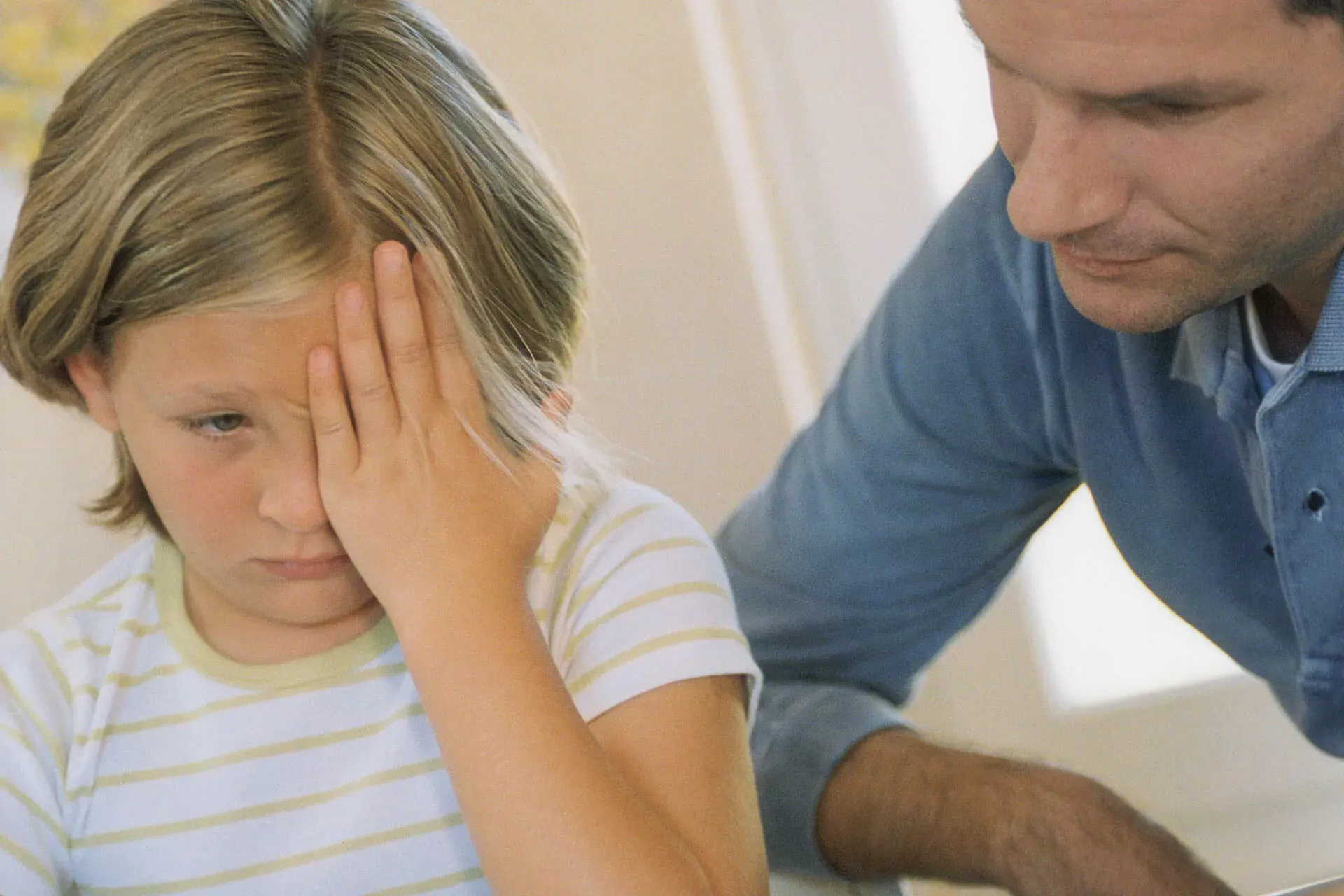 Mädchen im Grundschulalter quält sich beim Lernen, ein Erwachsener sitzt daneben. Mädchen im Grundschulalter quält sich beim Lernen, ein Erwachsener sitzt daneben.