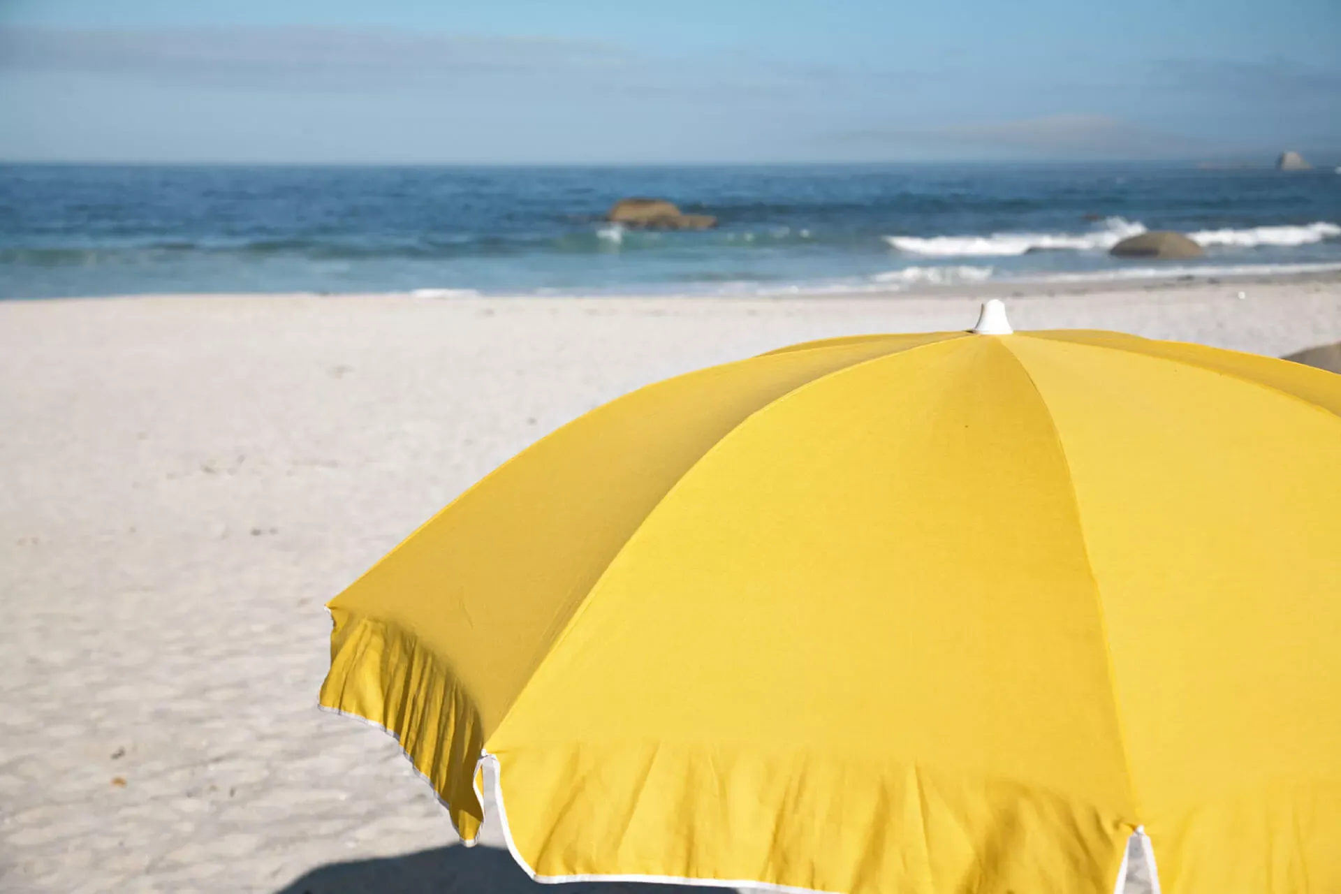 Gelber Sonnenschirm mit Sandstrand und Meer im Hintergrund. Gelber Sonnenschirm mit Sandstrand und Meer im Hintergrund.