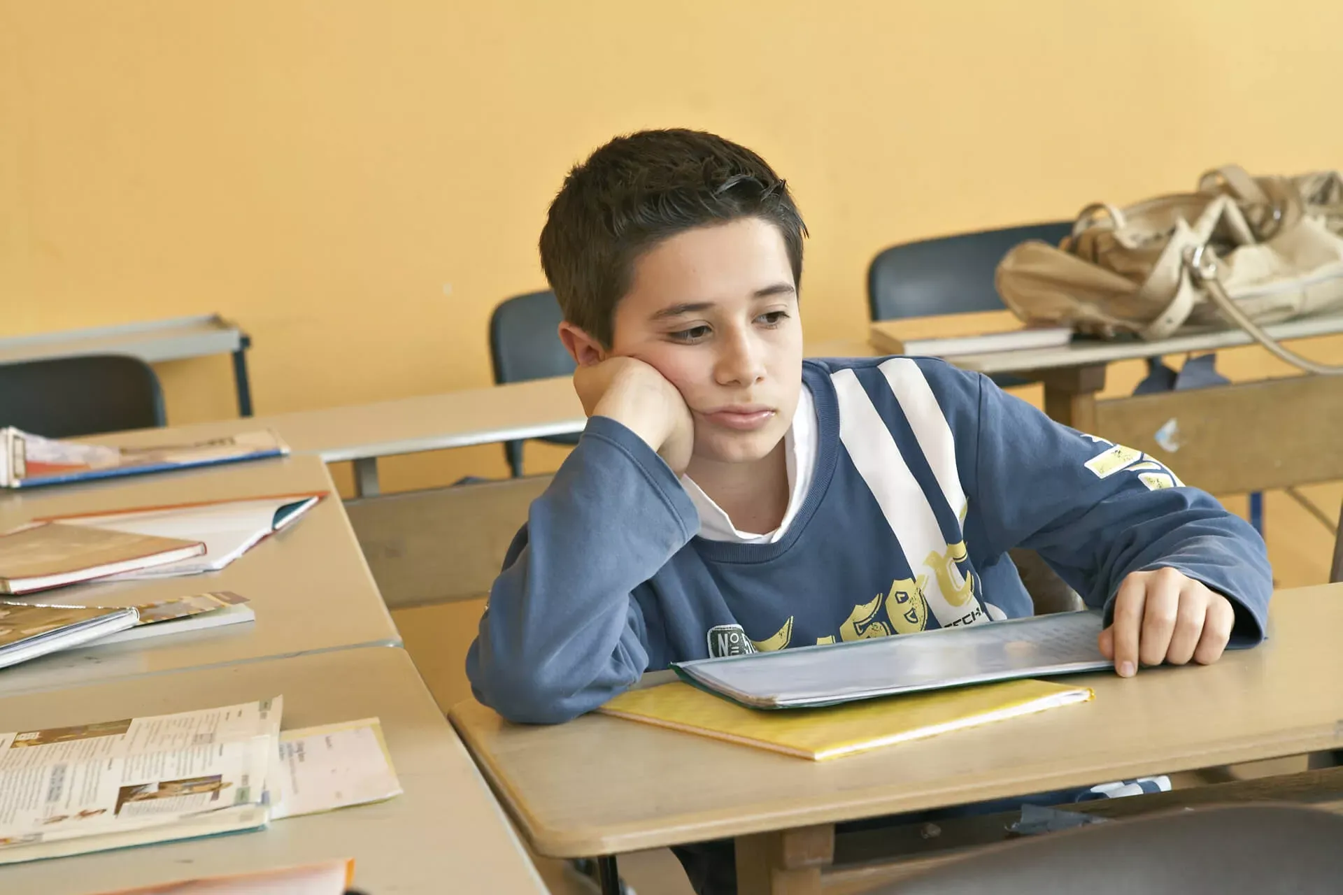 Schüler sitzt in einem leeren Klassenzimmer und schaut deprimiert. Schüler sitzt in einem leeren Klassenzimmer und schaut deprimiert.