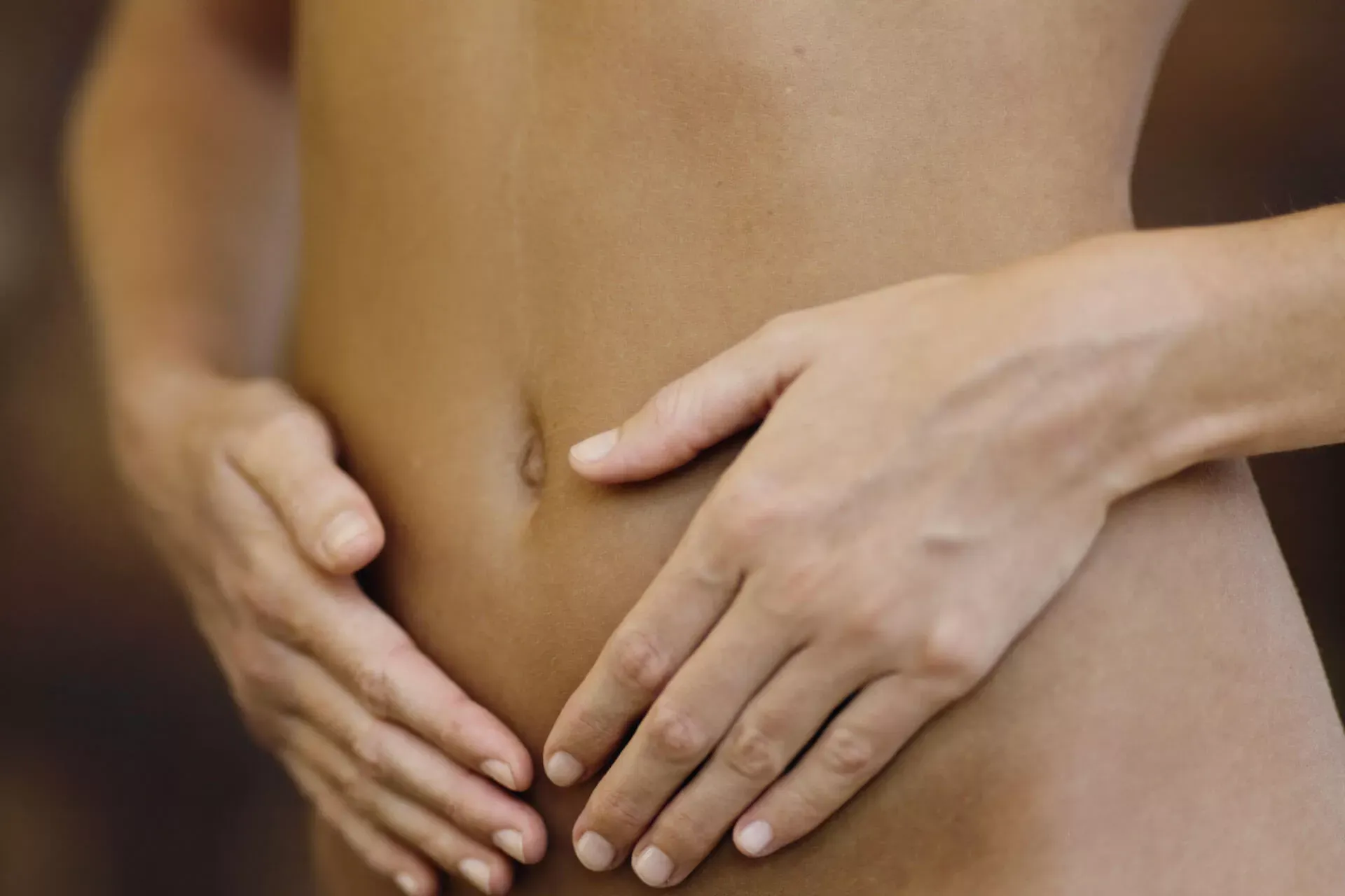 Junge Frau legt beide Hände auf ihren Bauch. Junge Frau legt beide Hände auf ihren Bauch.