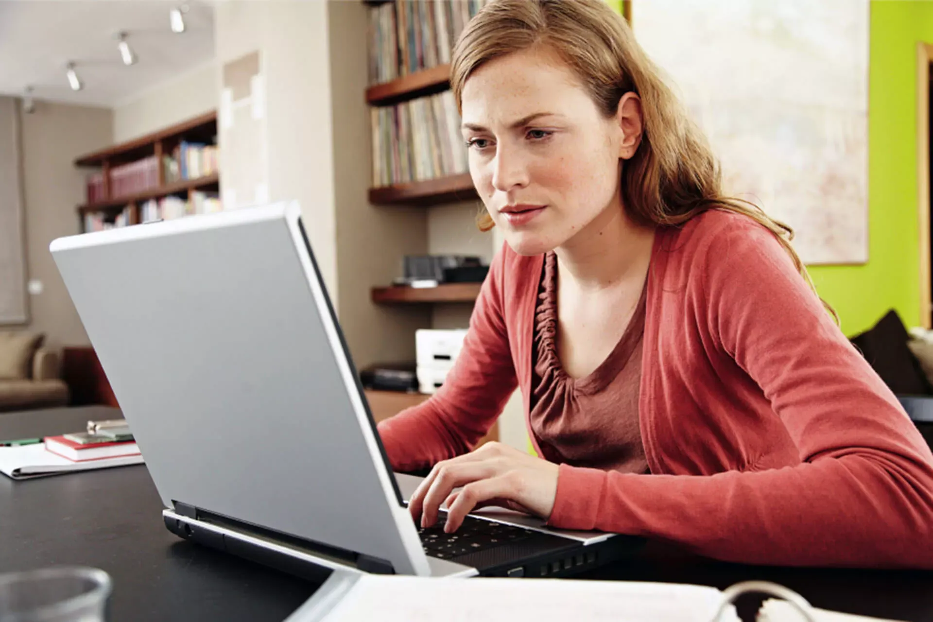 Junge Frau sitzt zuhause im Homeoffice am Notebook und schaut konzentriert auf den Bildschirm. Junge Frau sitzt zuhause im Homeoffice am Notebook und schaut konzentriert auf den Bildschirm.